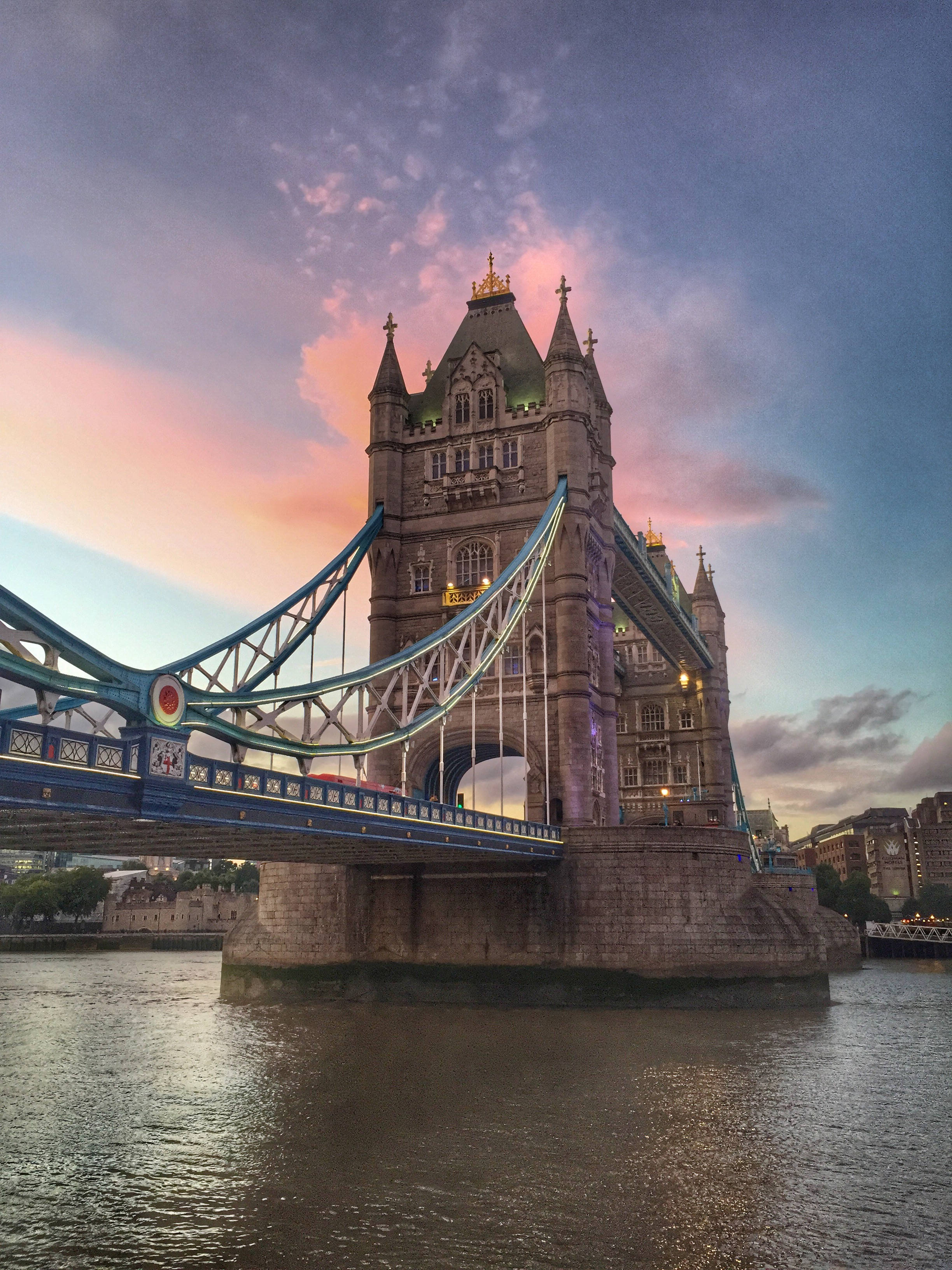 bridge 桌布 壁紙 — 倫敦的塔橋在充滿活力的暮色天空下閃耀，其藍色懸索結構倒映在泰晤士河上。