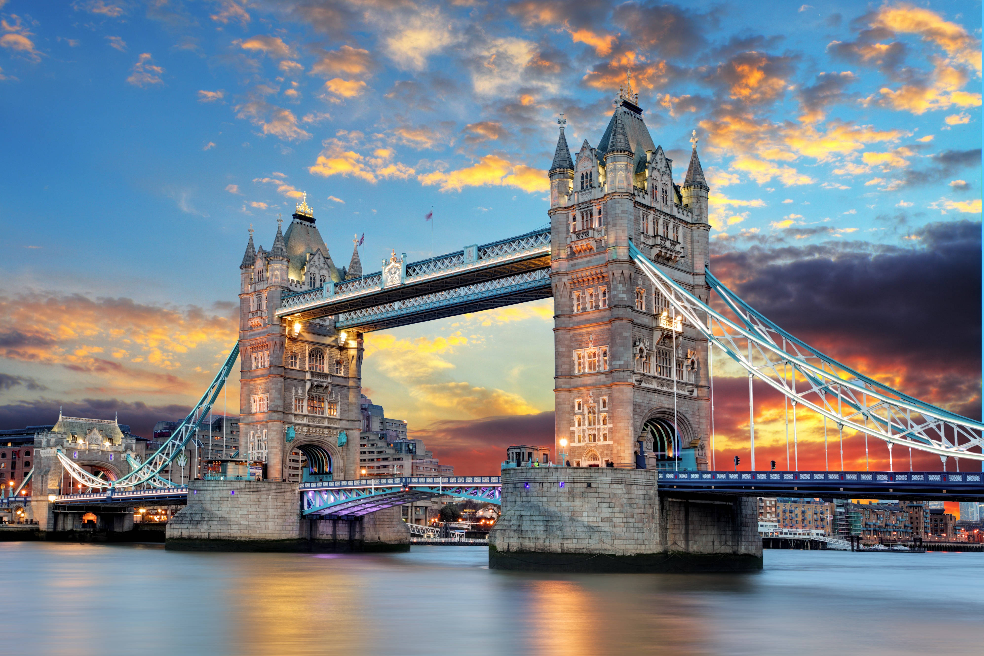 England 桌布 壁紙 — 倫敦的塔橋在壯麗的日落天空下溫暖地發光，伴隨著橙色的雲彩和寧靜的河面倒影。
