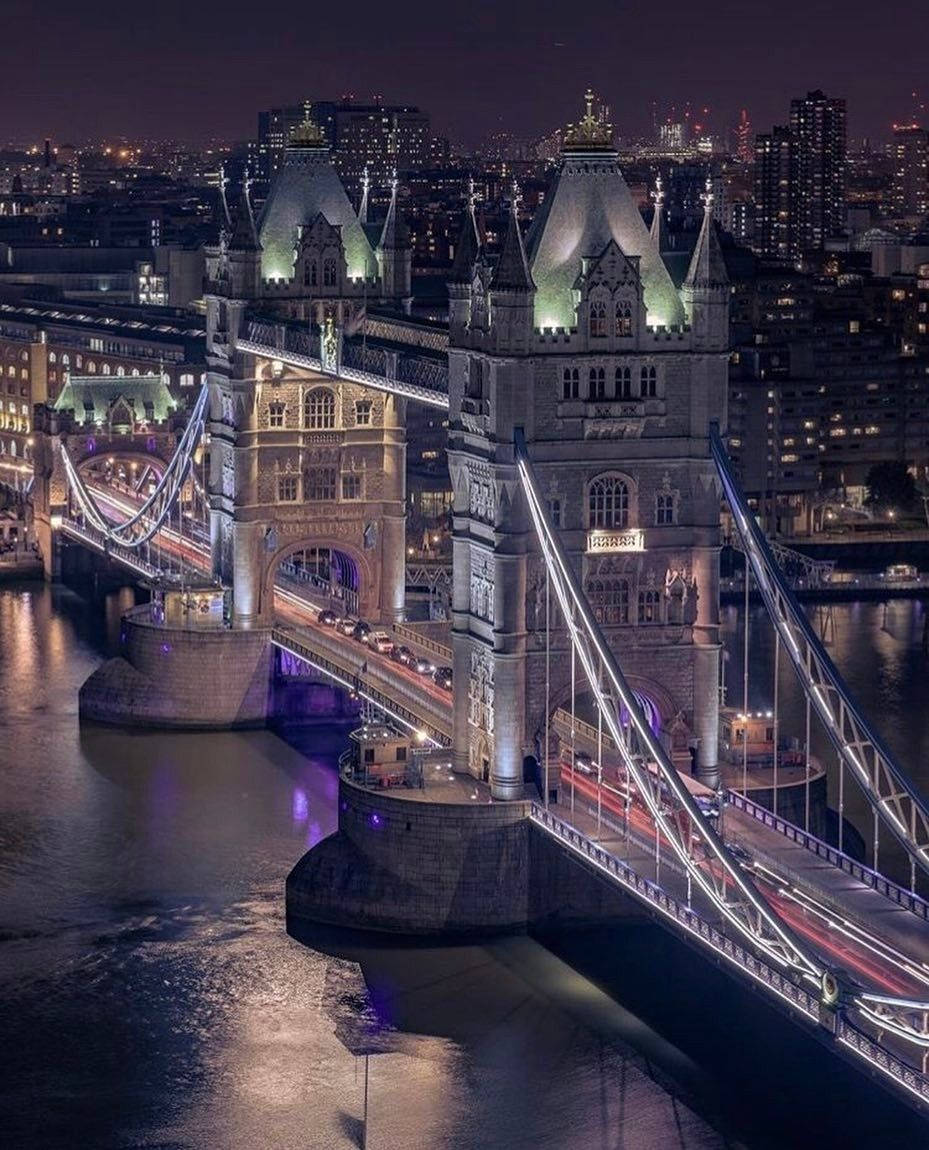 big ben 桌布 壁紙 — 倫敦的塔橋在夜晚閃耀著溫暖的燈光，倒映在下面的泰晤士河上。