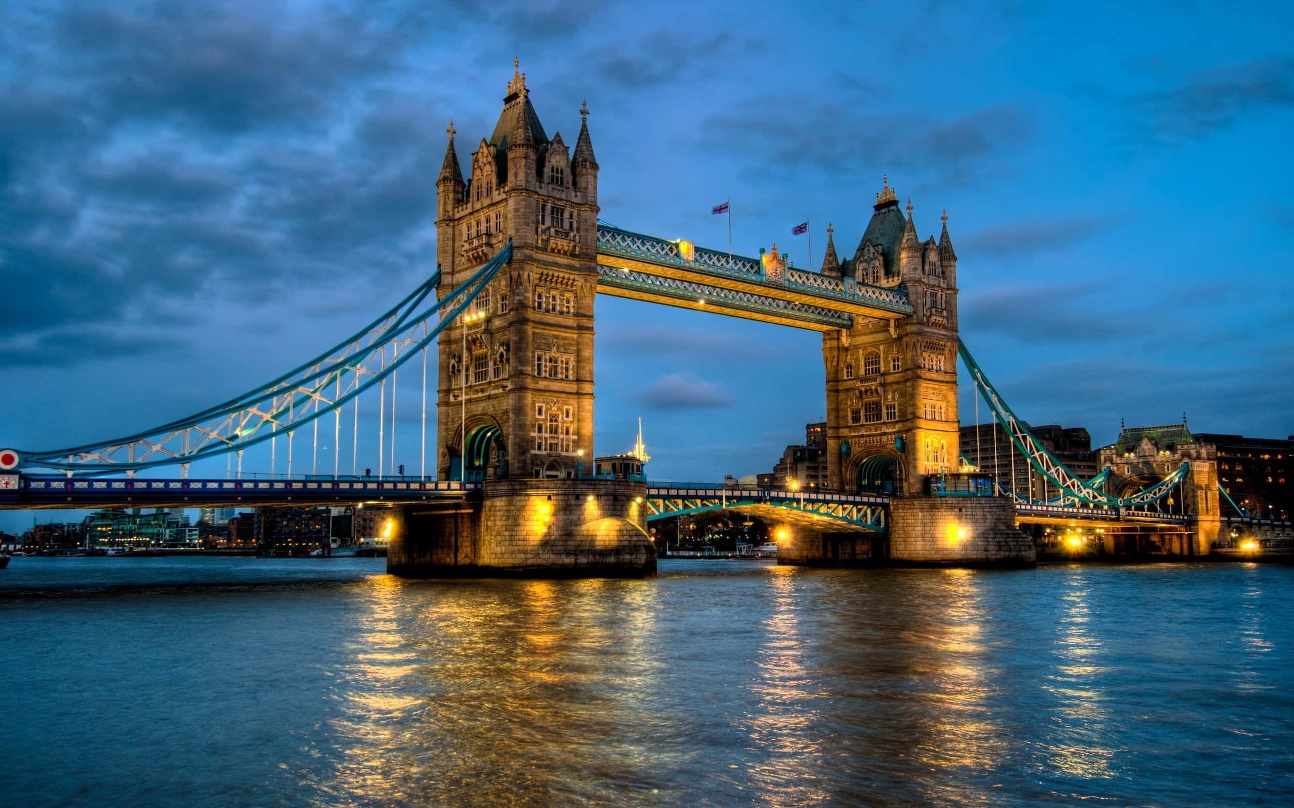 England 桌布 壁紙 — 倫敦的塔橋在暮色天空中溫暖地發光，其燈光倒映在下面的泰晤士河上。