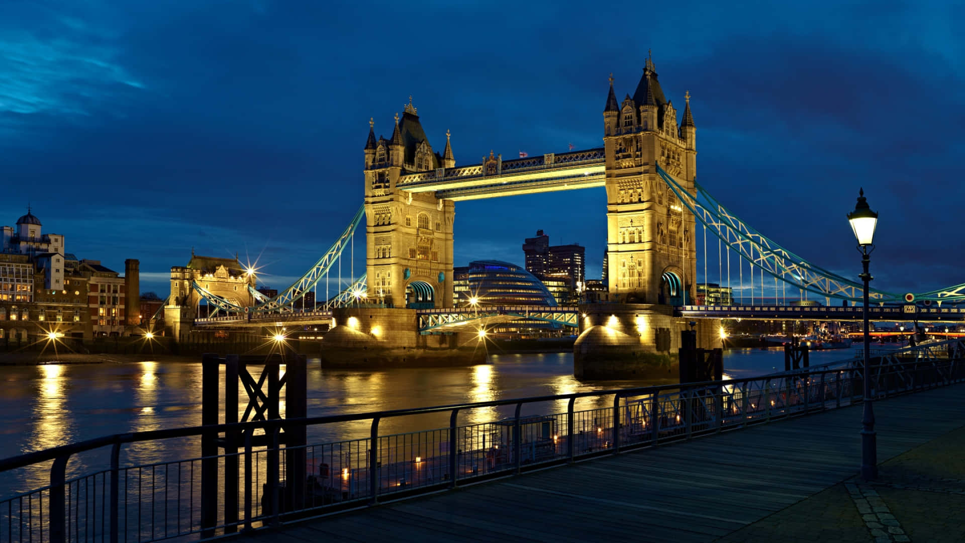 England 桌布 壁紙 — 倫敦的塔橋在深藍色的暮色天空中溫暖地發光，燈光倒映在下面的泰晤士河上。