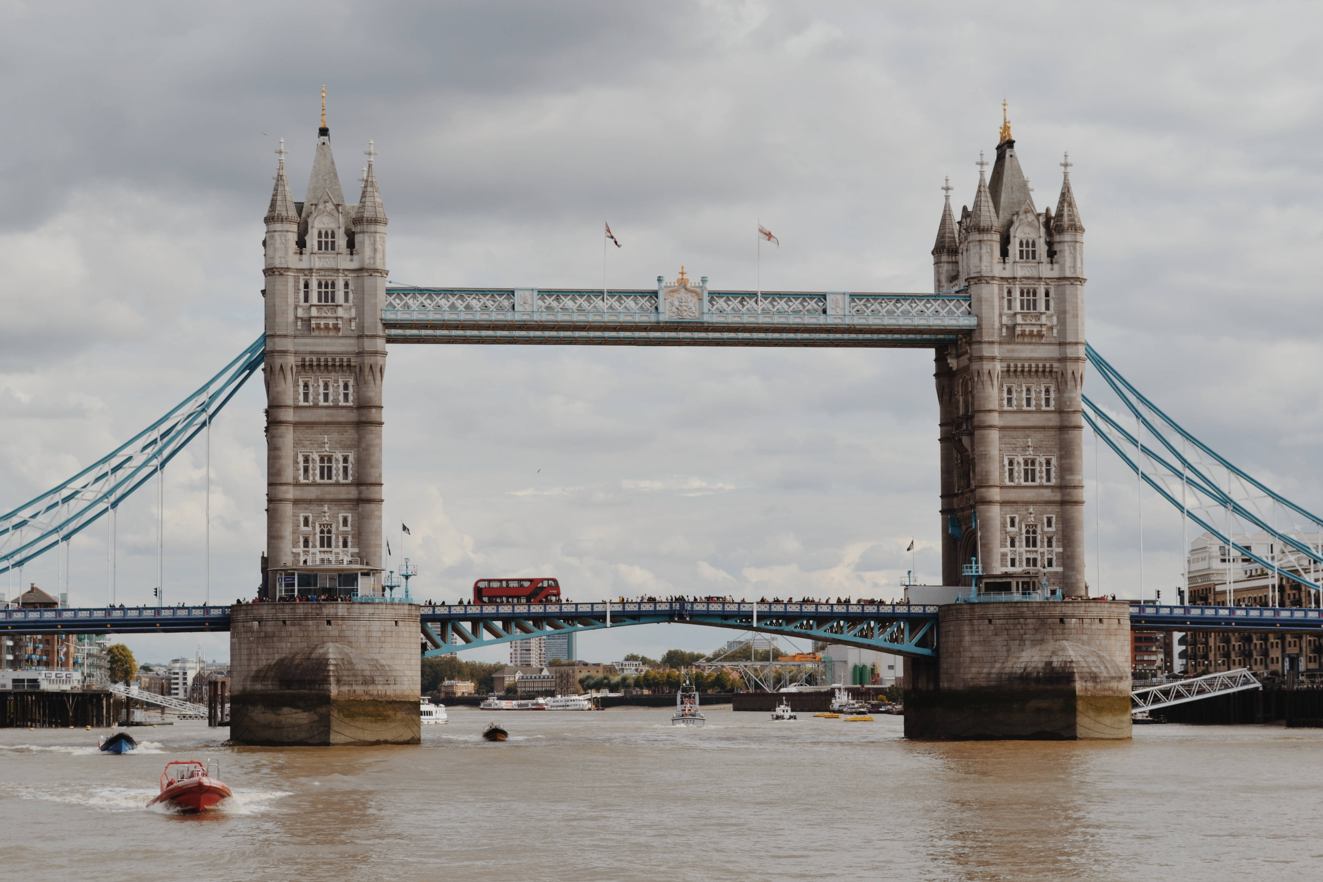 bridge 桌布 壁紙 — 倫敦的塔橋雄偉地矗立在泰晤士河上，一輛紅色雙層巴士在陰天天空下行駛。