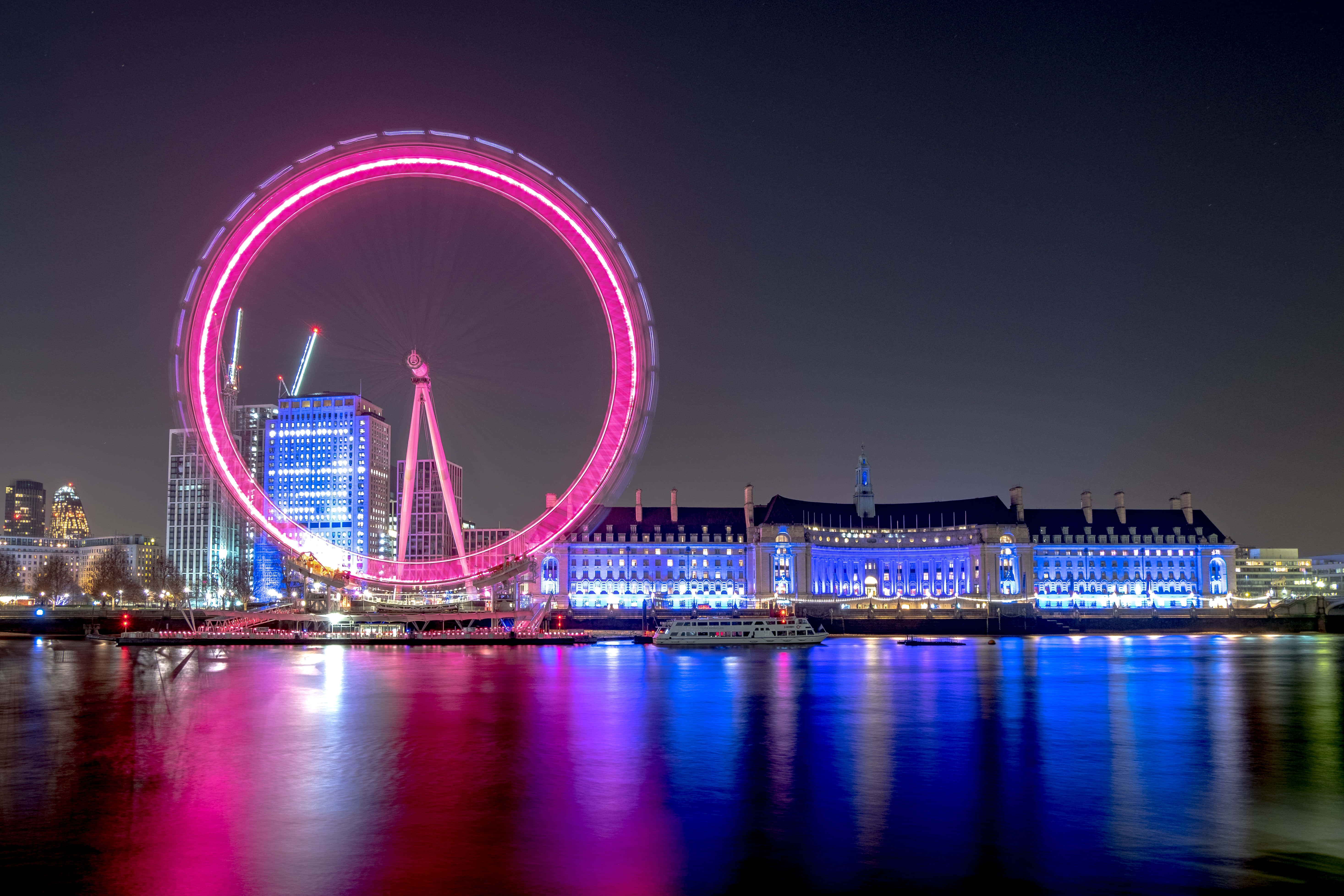 England 桌布 壁紙 — 倫敦眼在夜空中發出粉紅色的光芒，其燈光生動地反射在下面的泰晤士河上。
