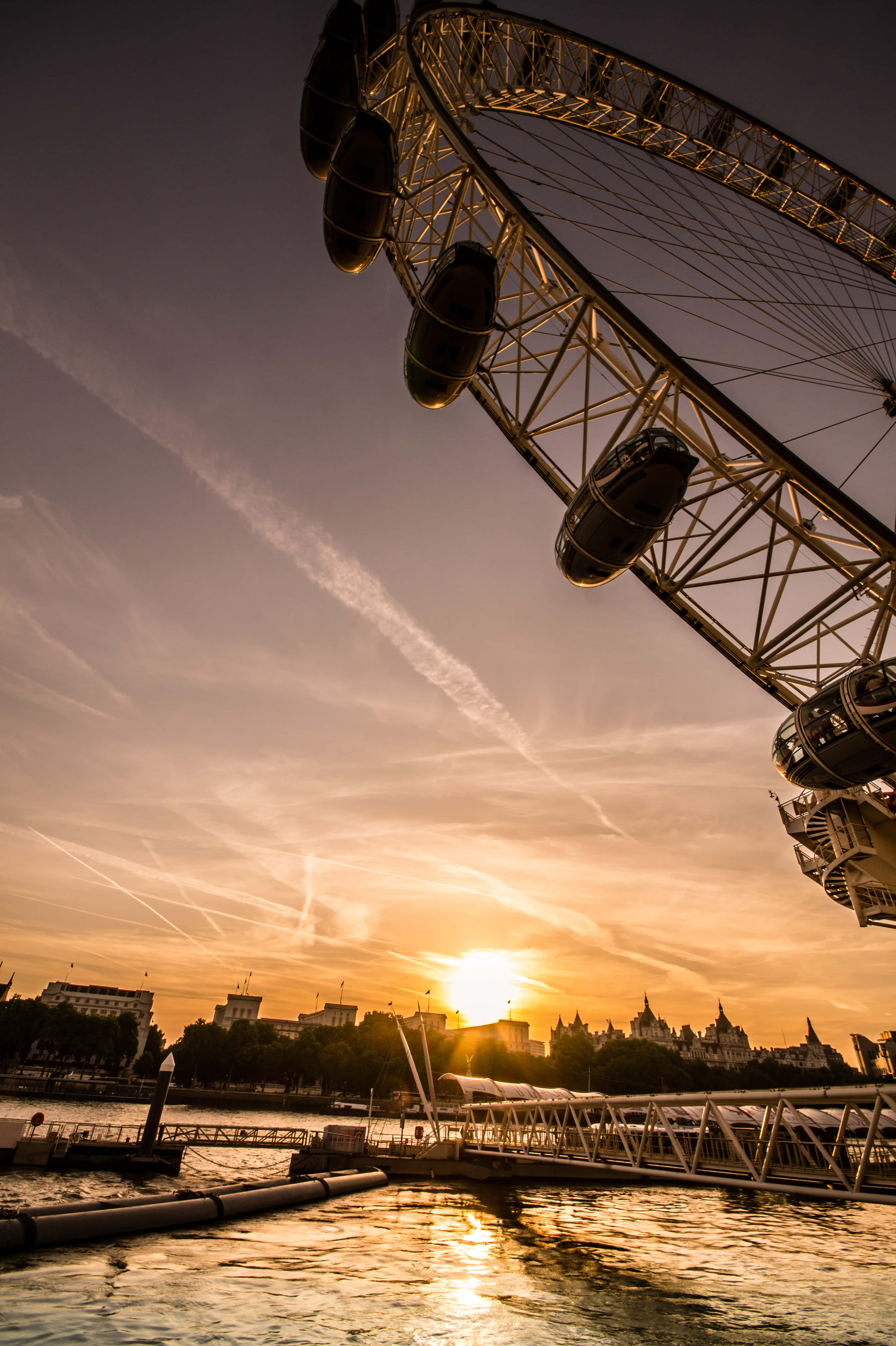 London iPhone 桌布 壁紙 — 倫敦眼在泰晤士河上主導著金色的日落，城市天際線的剪影和漣漪的水面倒影。