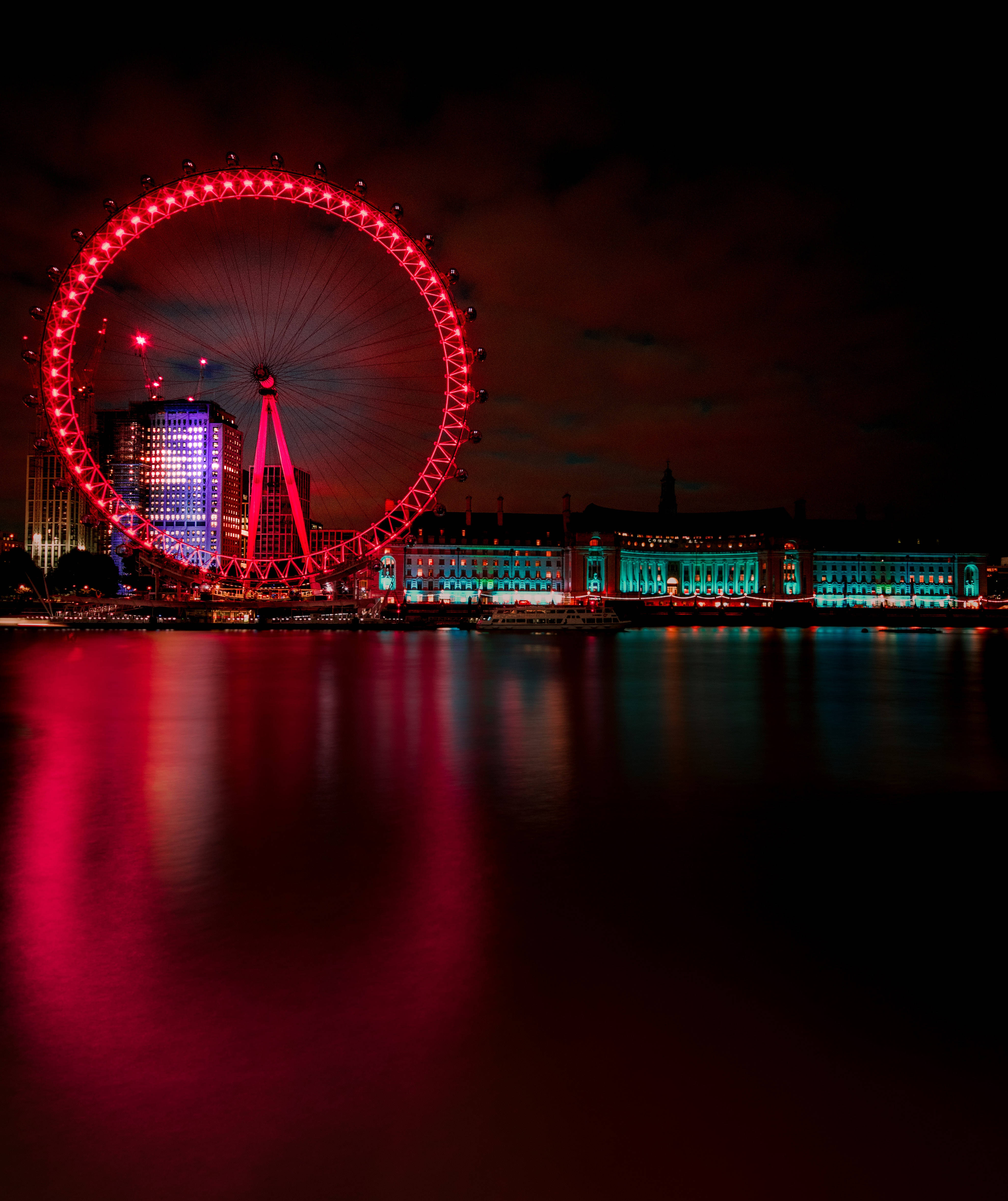 United Kingdom 桌布 壁紙 — 倫敦眼在漆黑的夜空下發出鮮豔的紅光，其燈光生動地倒映在下方平靜的泰晤士河水面上。