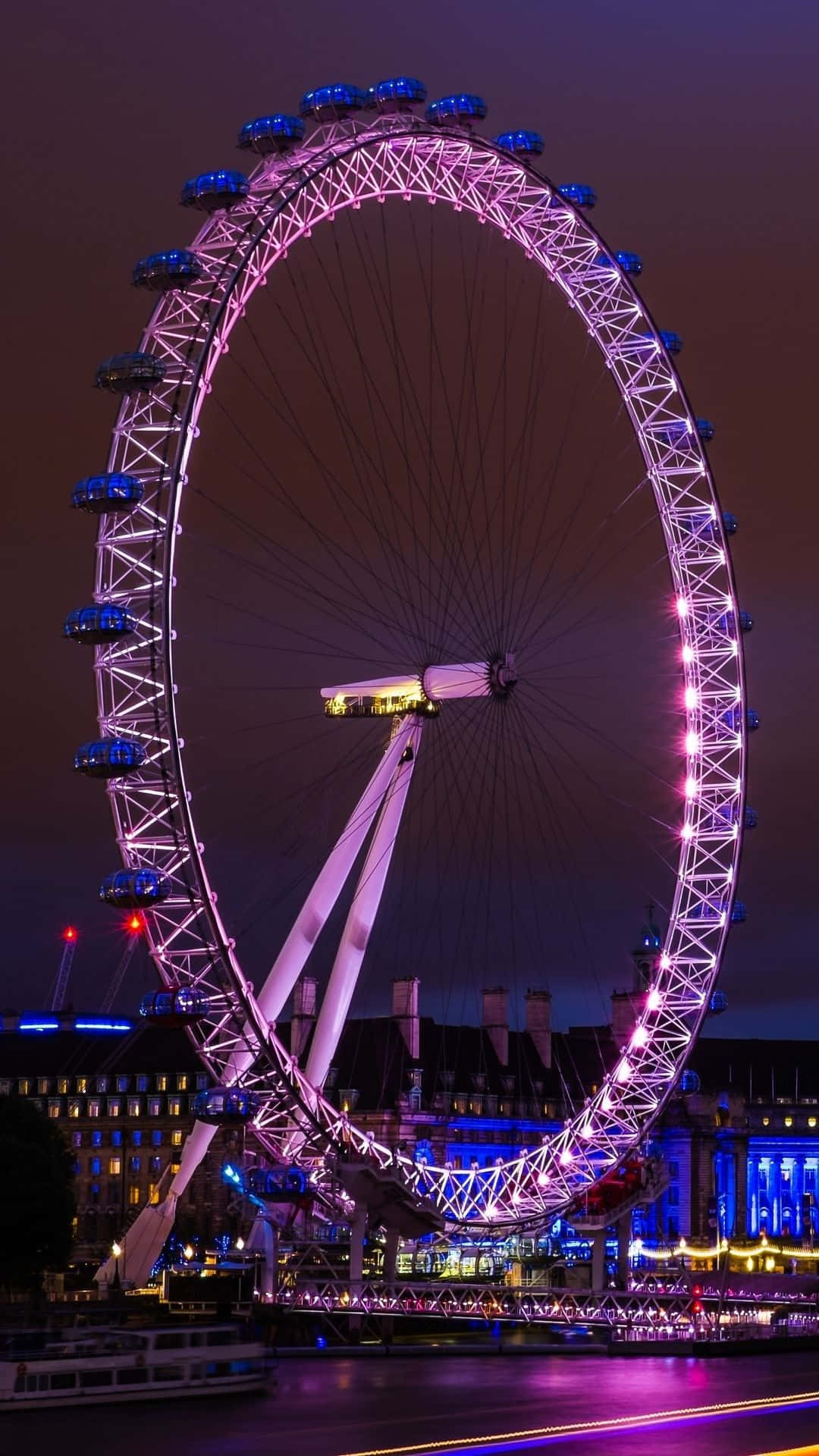 England 桌布 壁紙 — 倫敦眼在漆黑的夜空中閃耀著鮮豔的紫色和藍色燈光，倒映在下面的泰晤士河上。