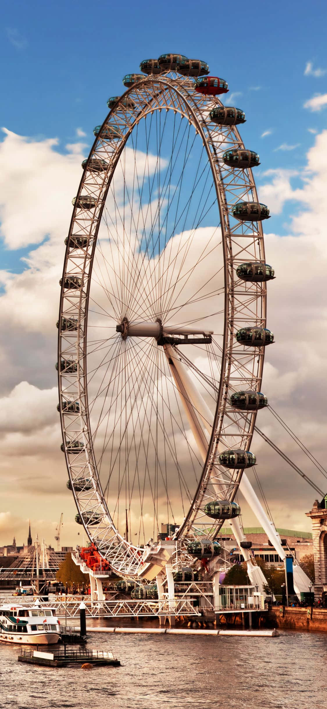 England 桌布 壁紙 — 倫敦眼在部分多雲的天空下高聳矗立，下方的河上有船隻漂浮。