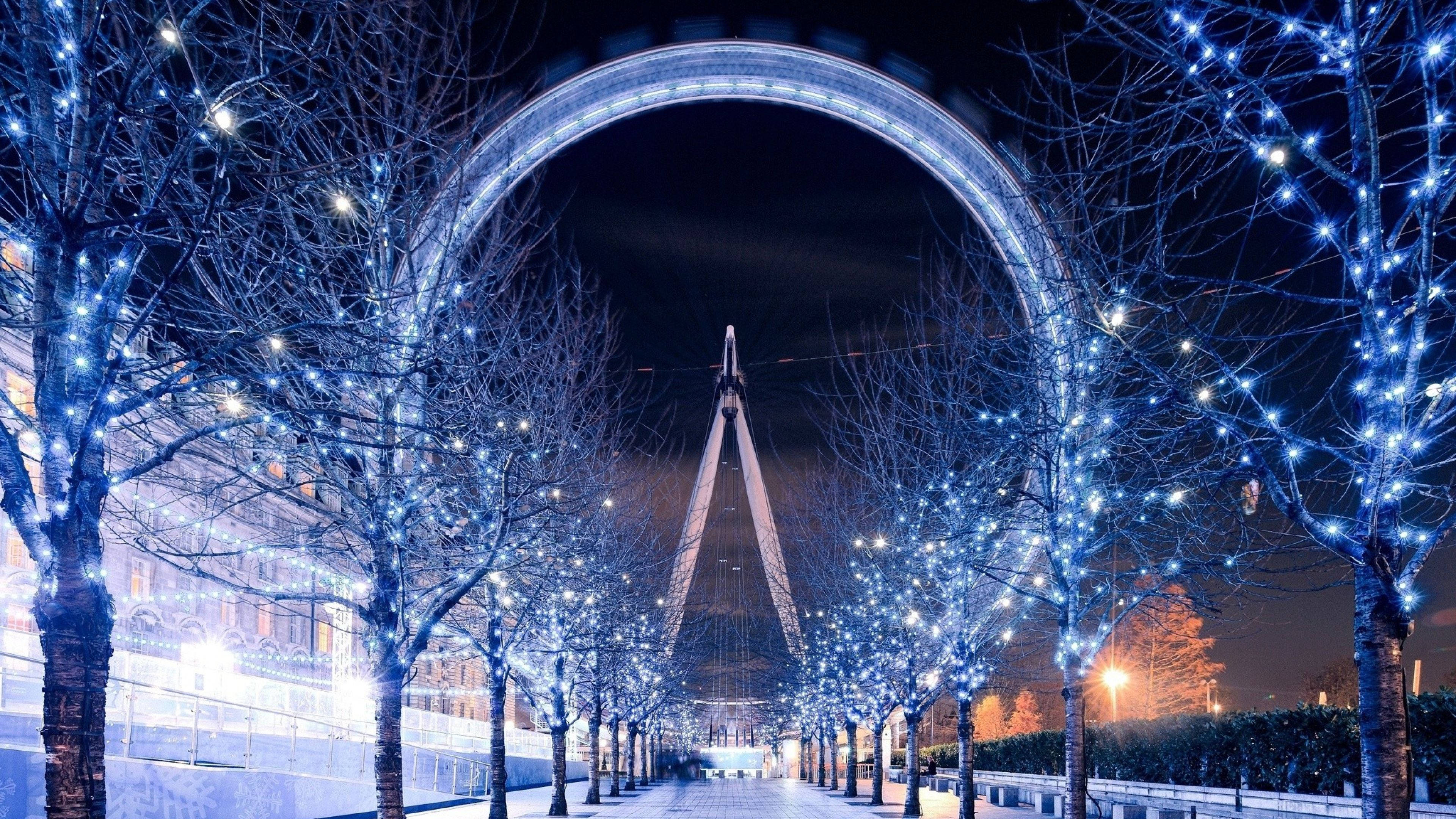 Wheel 桌布 壁紙 — 倫敦眼的璀璨夜景，襯托著掛滿藍色仙女燈的禿樹。