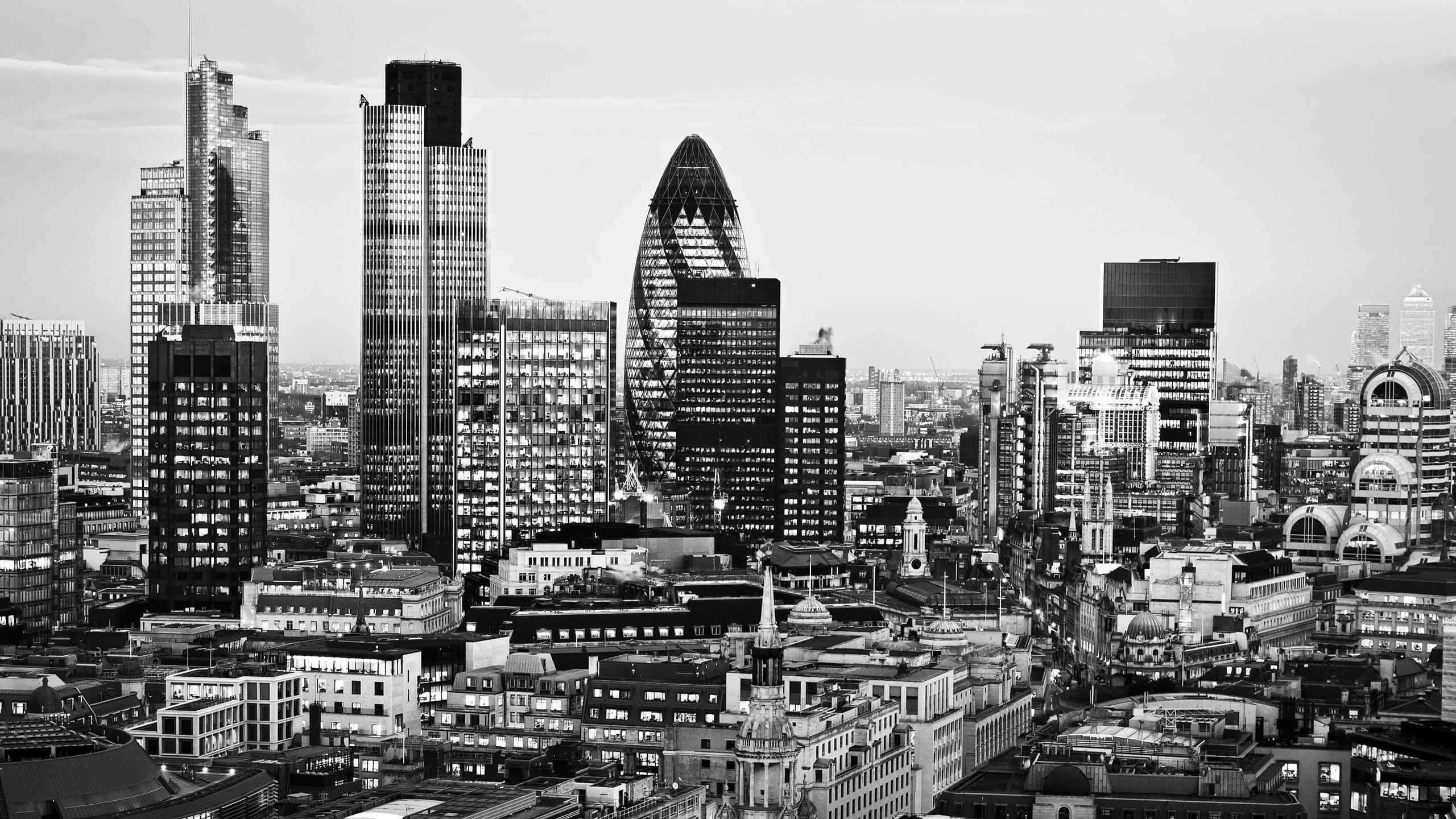 Black And White Cityscape 桌布 壁紙 — 倫敦金融區的單色航拍視圖，展示在柔和天空下的現代摩天大樓和歷史建築。