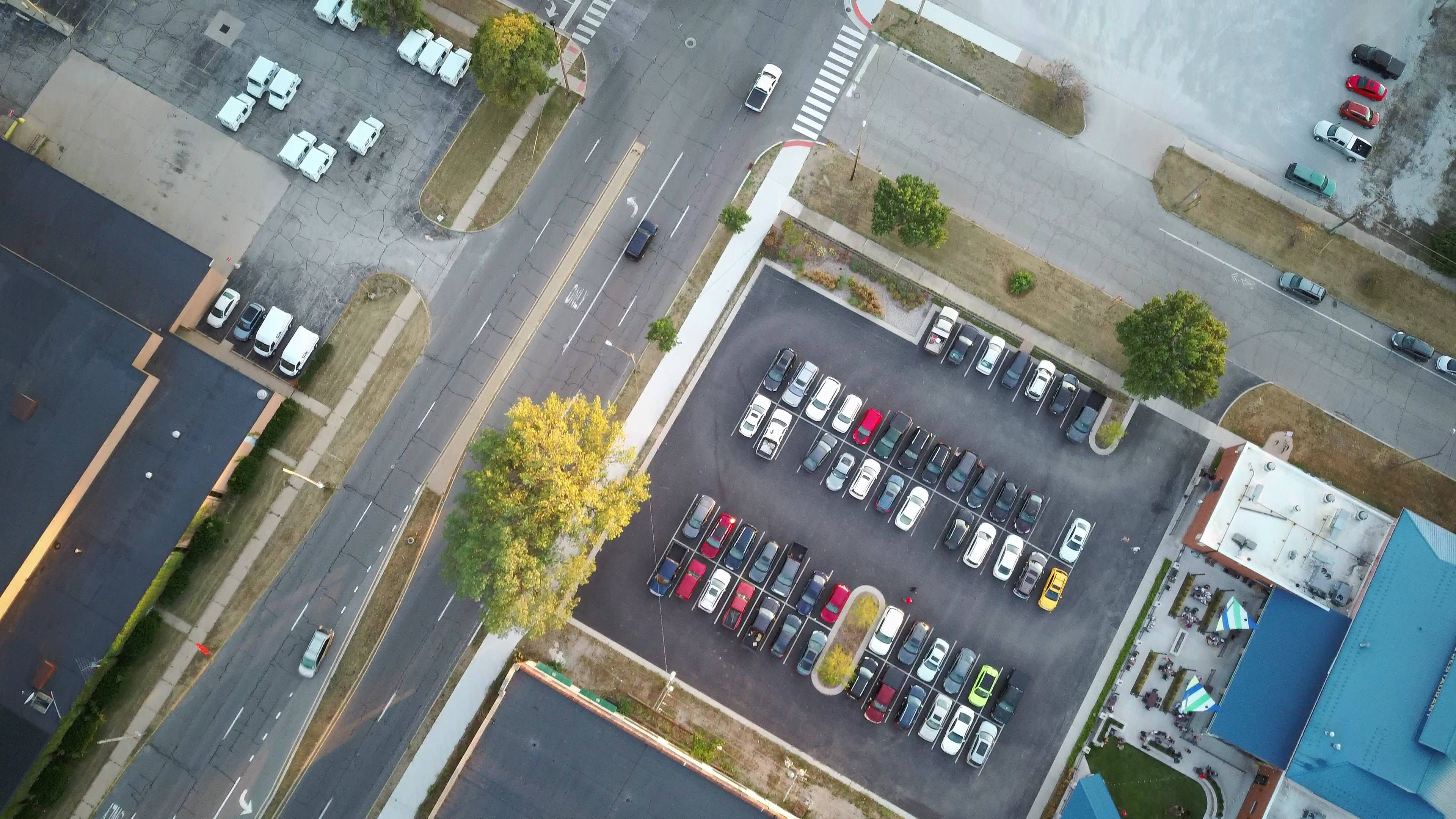Road 桌布 壁紙 — 停車場和街道交匯處的鳥瞰圖，汽車和秋樹在晴朗的日光下。