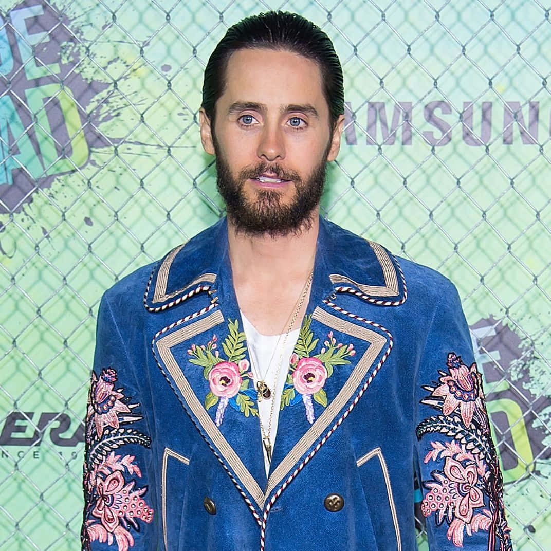 jared leto 桌布 壁紙 — 傑克·葛倫霍站在鐵絲網圍欄前，身穿帶有粉紅色花卉刺繡的藍色天鵝絨外套。