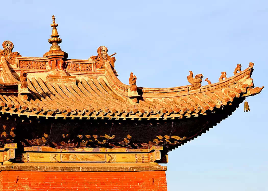 Mongolia 桌布 壁紙 — 傳統中國寺廟的金色瓦頂，上有華麗的脊獸，襯著清澈的藍天。