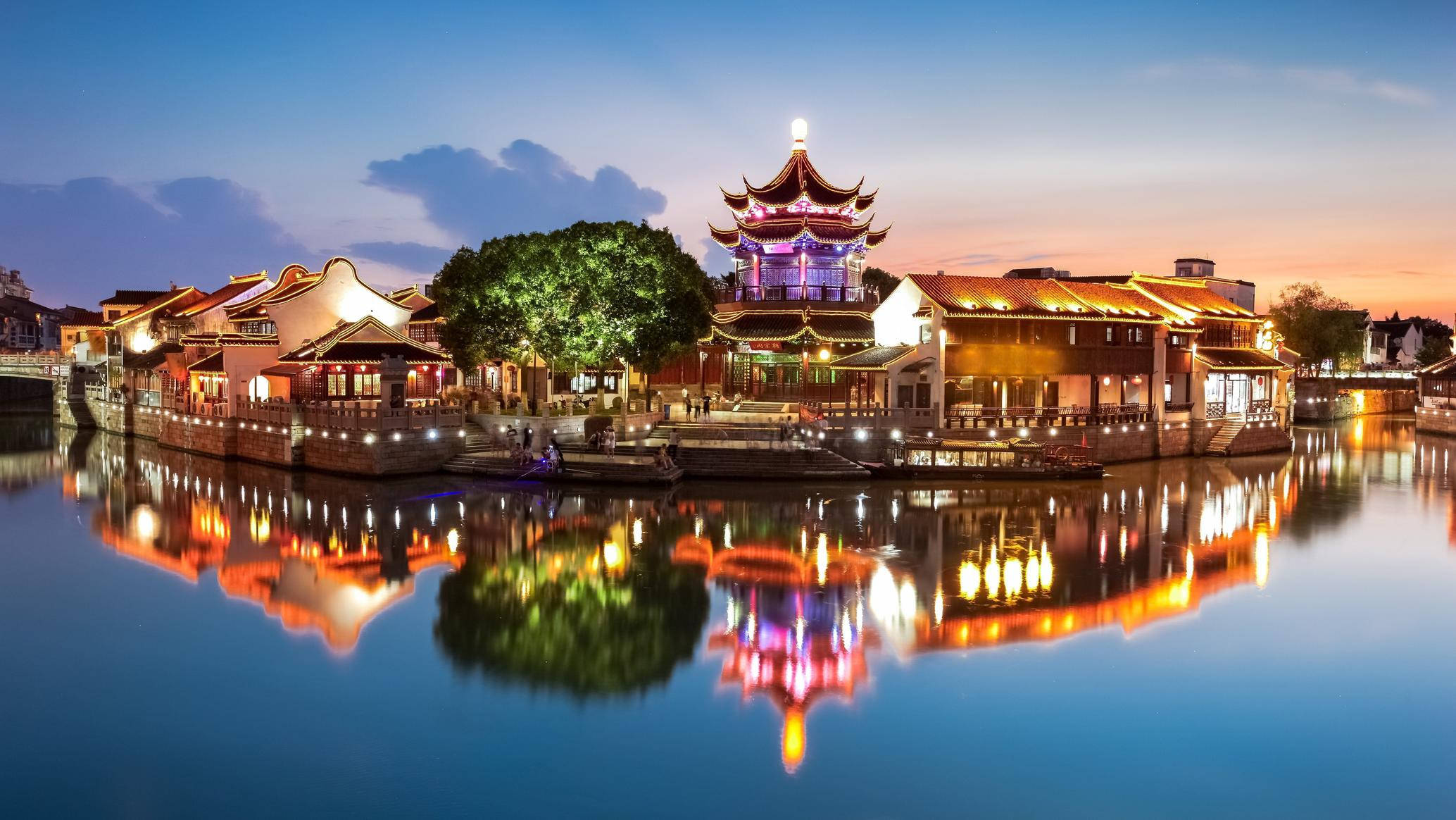 Suzhou 桌布 壁紙 — 傳統中國水鄉在黃昏時分，柔和藍天下，平靜水面倒映著發光的燈籠。