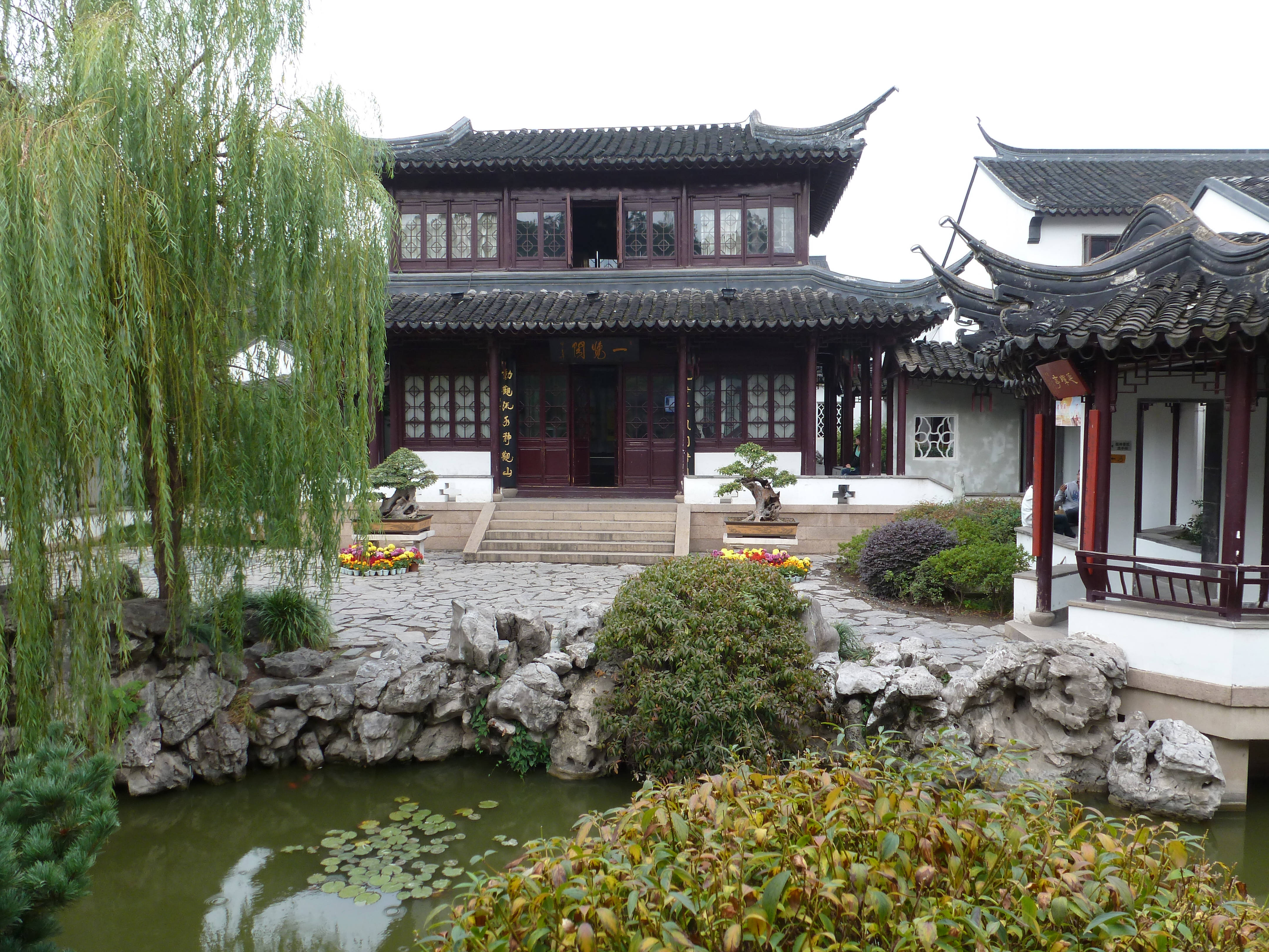Nanjing 桌布 壁紙 — 傳統中式亭閣，擁有彎曲屋頂和紅色柱子，坐落於池塘旁，池塘中有荷葉和垂柳。
