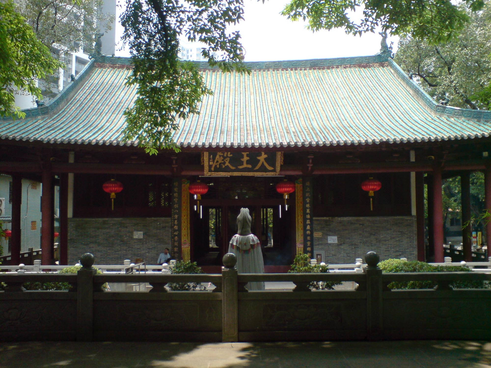 Guangzhou 桌布 壁紙 — 傳統中式寺廟，綠色瓦頂、紅色柱子和懸掛的燈籠，在晴朗的日子被茂密的樹木環繞。
