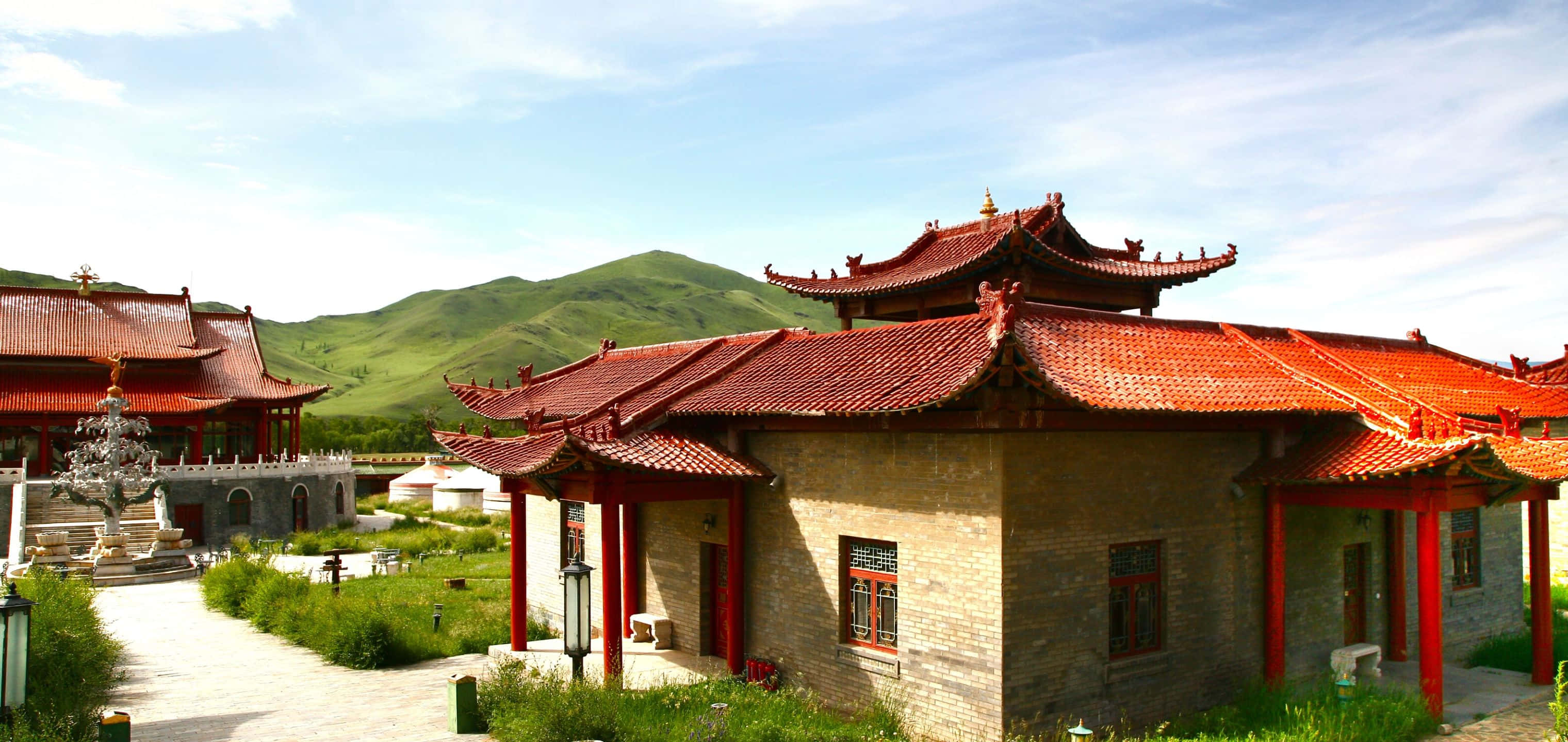 3040x1440 桌布 壁紙 — 傳統中式寺廟建築，紅瓦屋頂和木柱，矗立在青翠山丘之間，天空湛藍明亮。