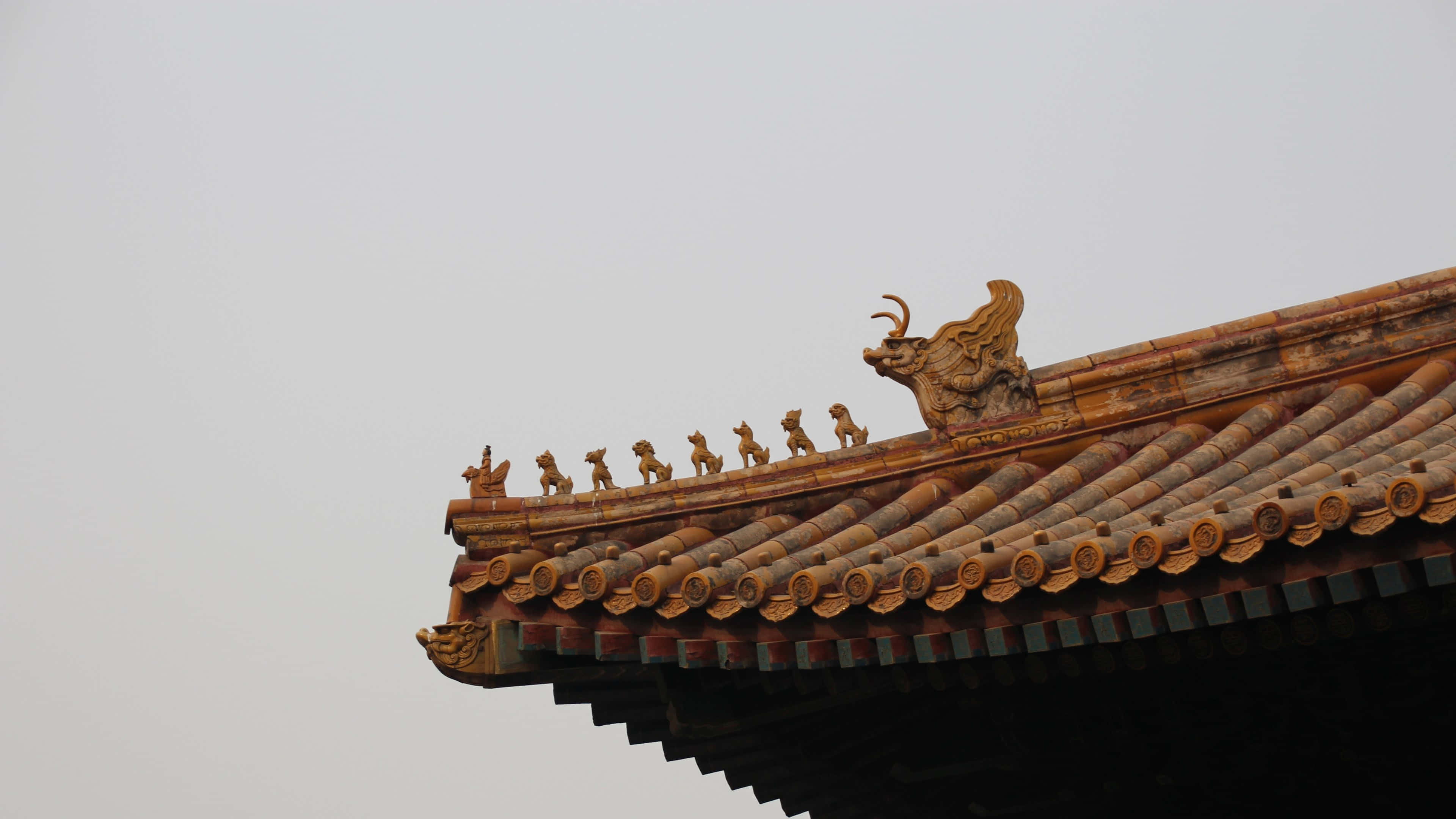 Roof 桌布 壁紙 — 傳統中式屋頂，飾有華麗的金龍和神話生物雕像，映襯著淡色天空。