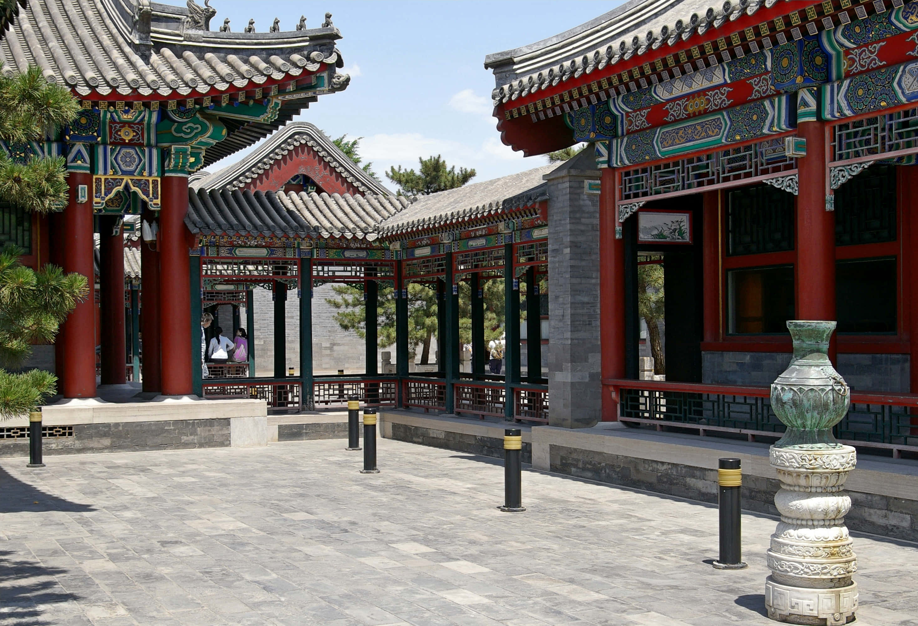 建築 桌布 壁紙 — 傳統中式庭院，紅柱、華麗屋頂和石鋪地面，在明亮的日光下。