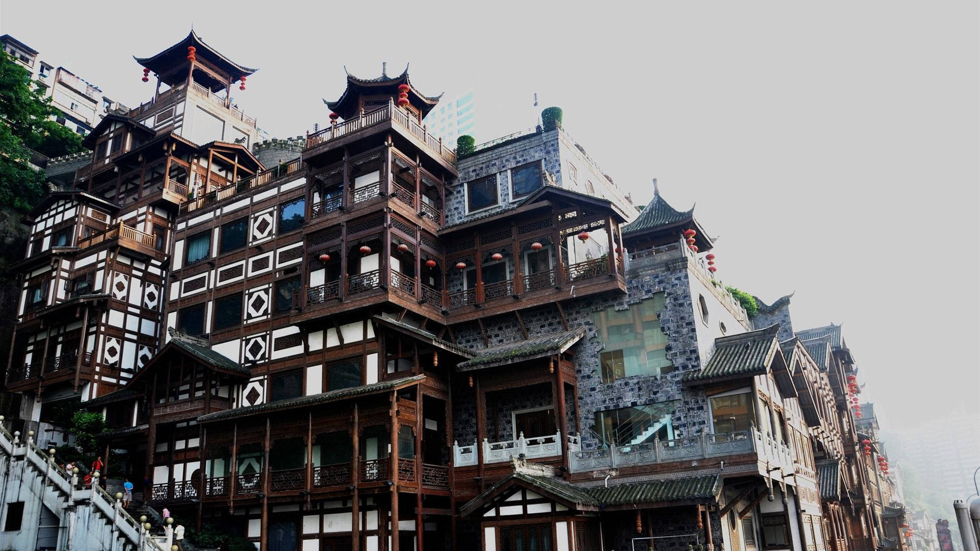 Chongqing 桌布 壁紙 — 傳統中式木建築，瓦頂和紅燈籠，依附在霧氣瀰漫的山坡上。