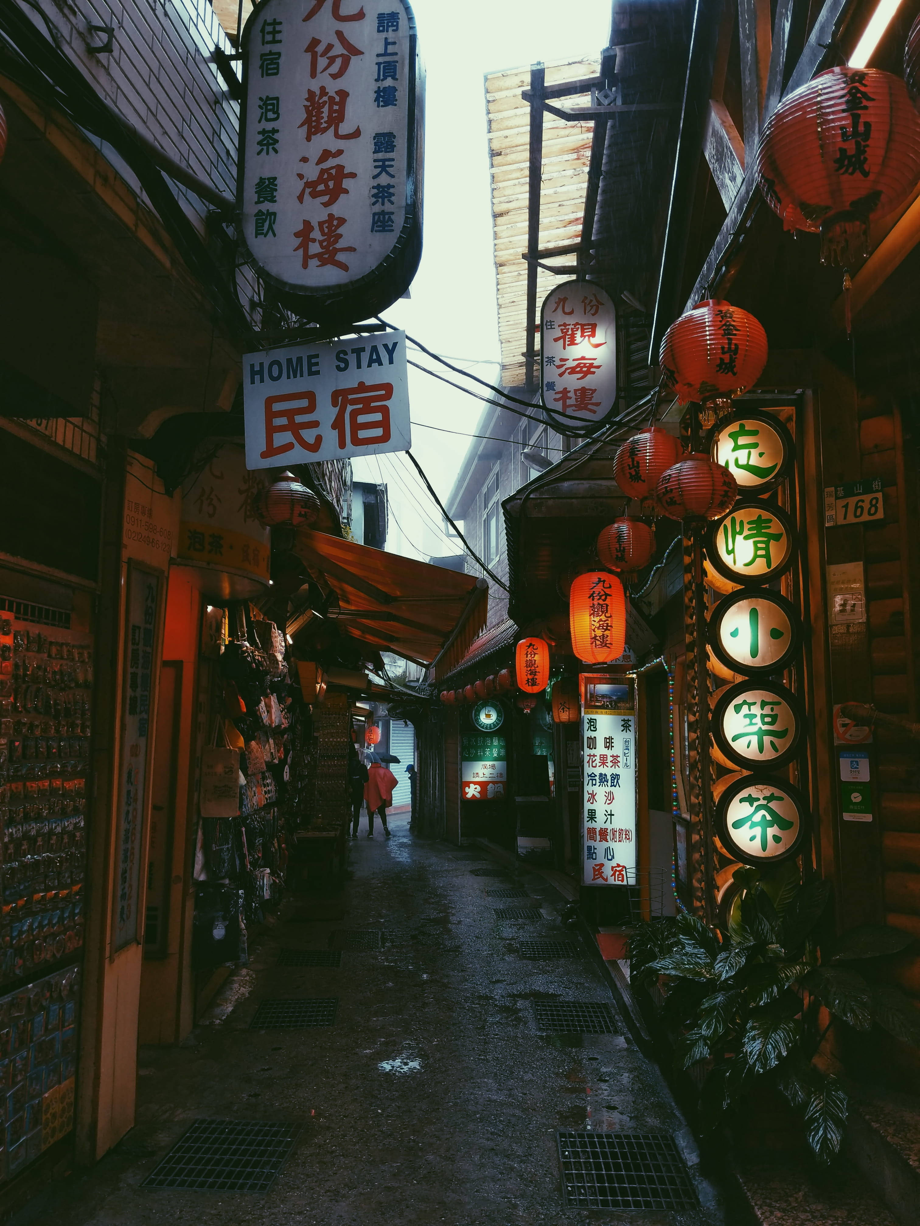 台灣 桌布 壁紙 — 傳統亞洲小鎮一條狹窄的雨巷，兩旁掛滿發光的燈籠和色彩繽紛的商店招牌。