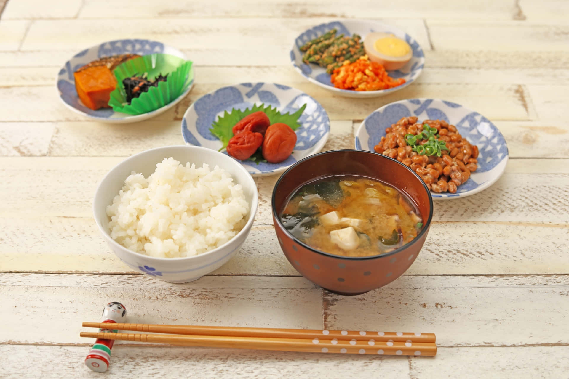 日式 桌布 壁紙 — 傳統日式餐點，包括米飯、味噌湯和小菜，擺放在質樸的白色木桌上。