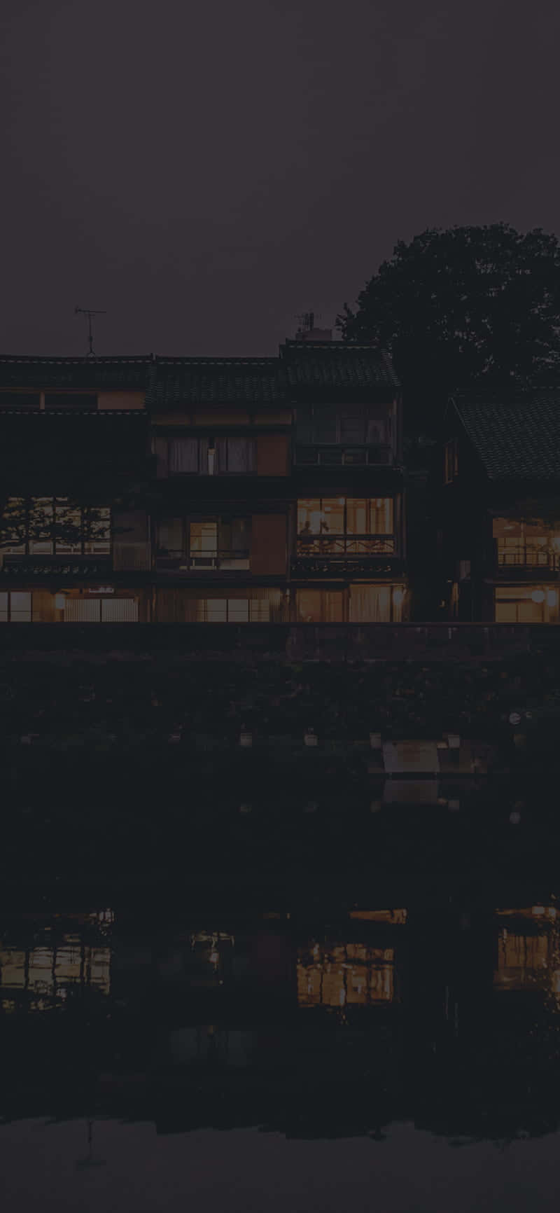 桌布 壁紙 — 傳統木屋的黑暗夜景，溫暖發光的窗戶倒映在平靜的水面上。