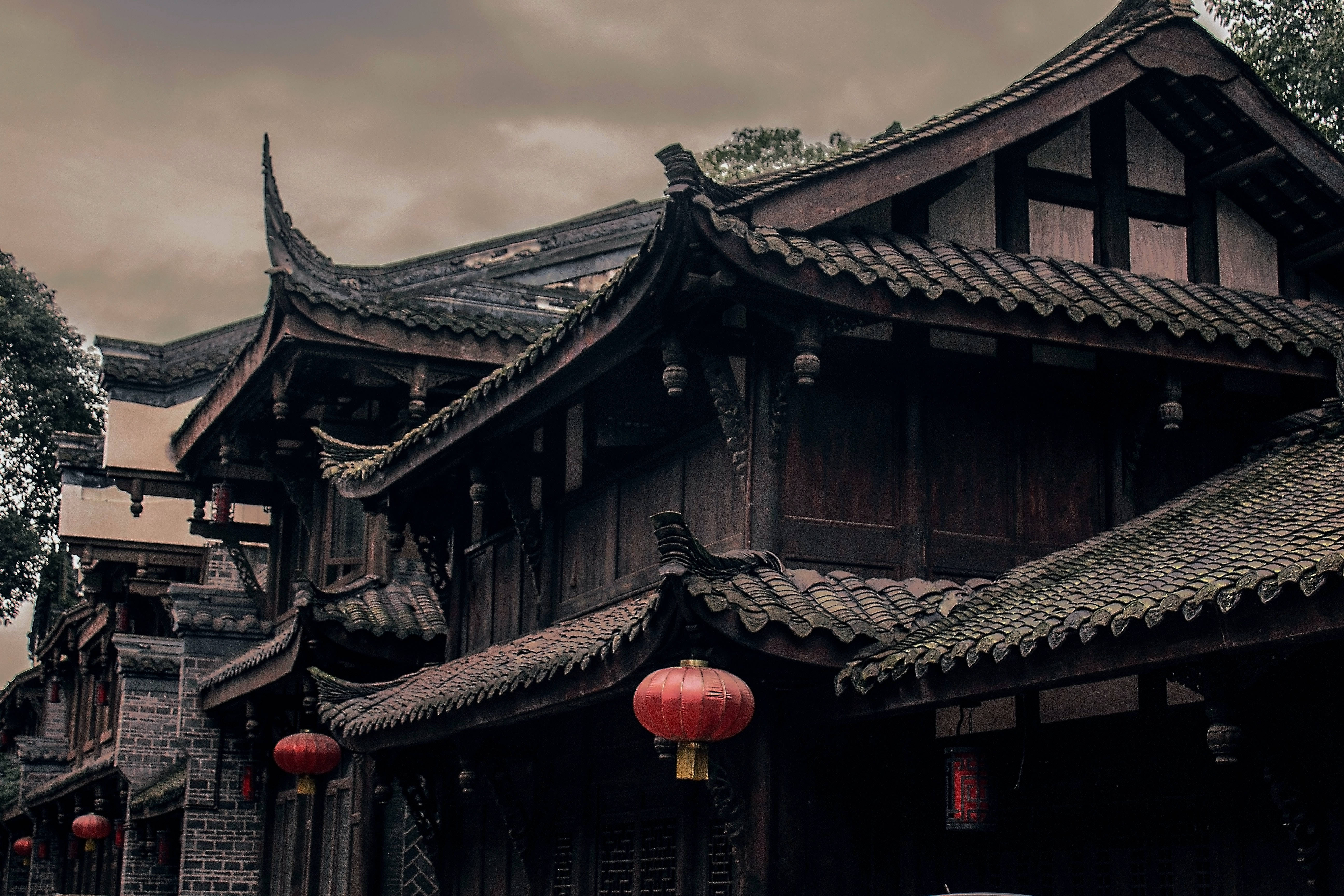 中式房屋壁紙 桌布 壁紙 — 傳統木造中式建築，曲線瓦頂和紅色燈籠，在陰沉多雲的天空下。