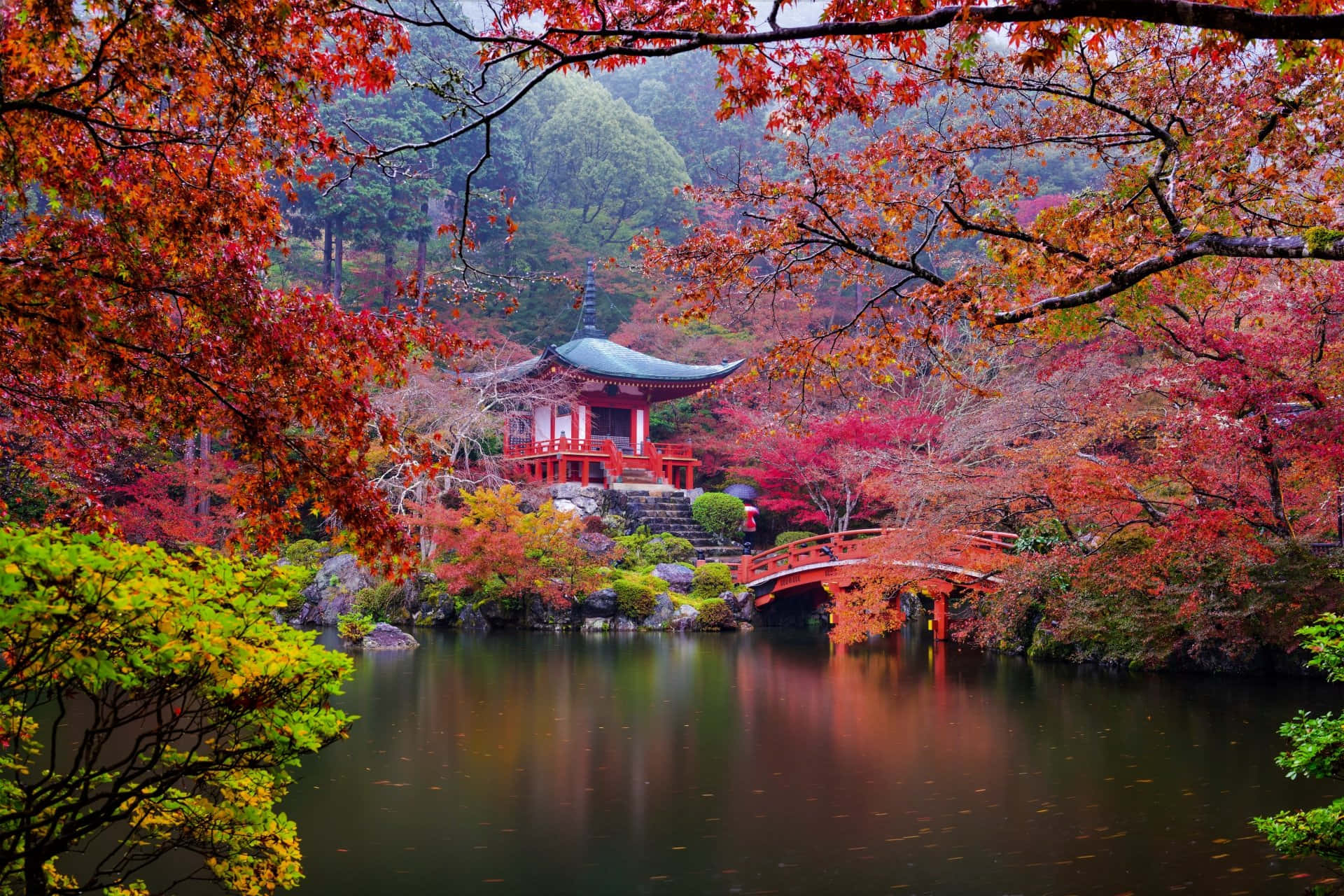 桌布 壁紙 — 傳統的紅色日本亭閣和拱橋倒映在平靜的水面上，周圍環繞著充滿活力的秋葉。