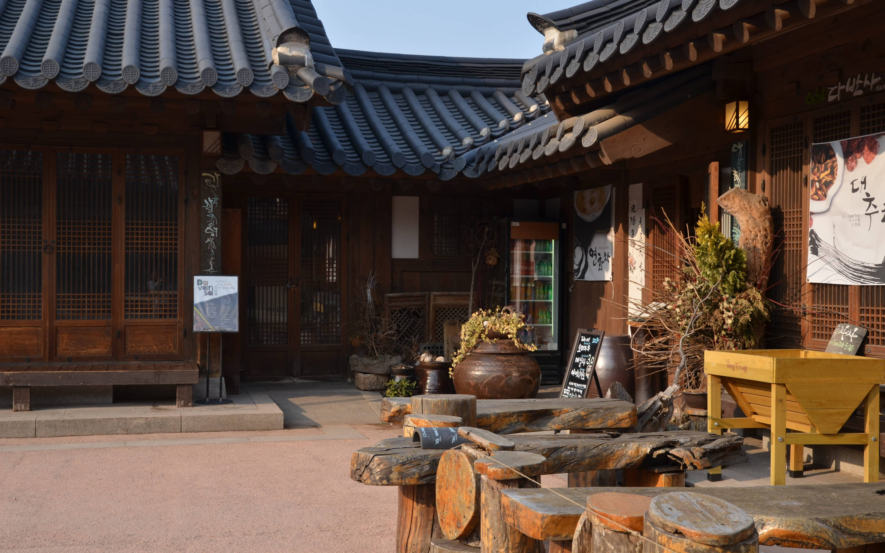 korean 桌布 壁紙 — 傳統韓國庭院，木造建築、彎曲瓦頂及質樸木桌，在清澈藍天下。
