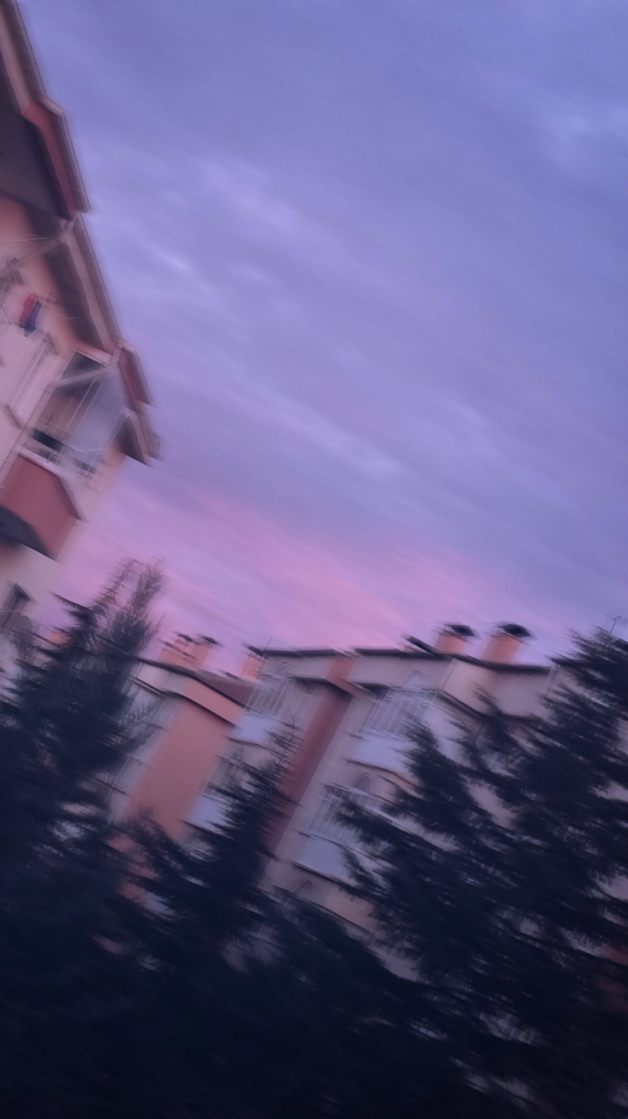 Tumblr Aesthetic 桌布 壁紙 — 傾斜視角下的住宅建築和樹木，背景是紫色和粉紅色的暮色天空，帶有動態模糊效果。