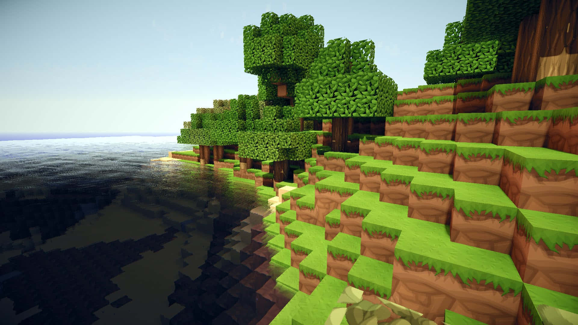 島嶼 桌布 壁紙 — 像素化Minecraft景觀中，塊狀的綠色樹木和長滿草的山崖從平靜的海水中升起，天空晴朗。