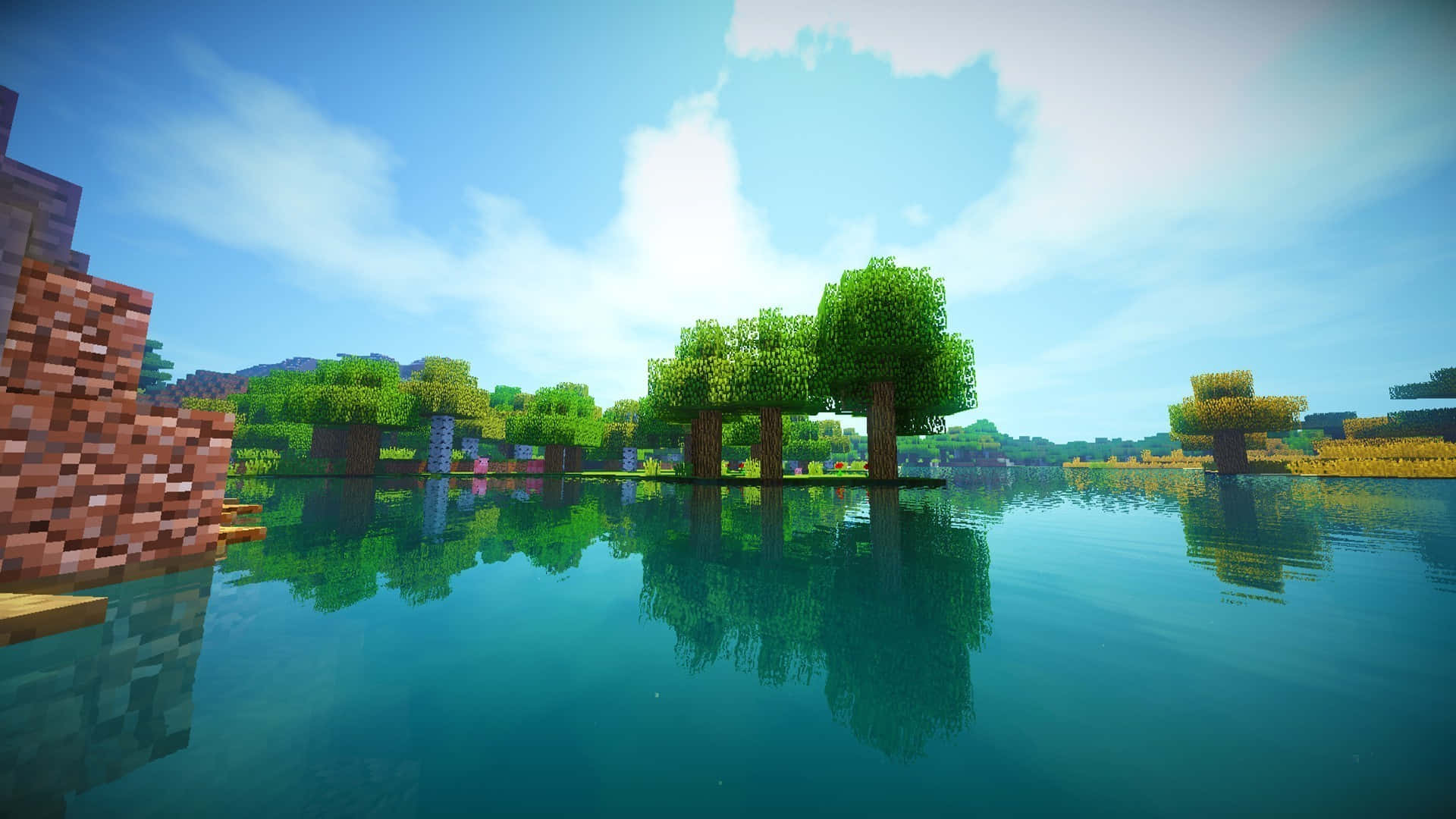 Lake 桌布 壁紙 — 像素化的 Minecraft 樹木和石塊在平靜的藍綠色水中倒映，天空湛藍，白雲朵朵。