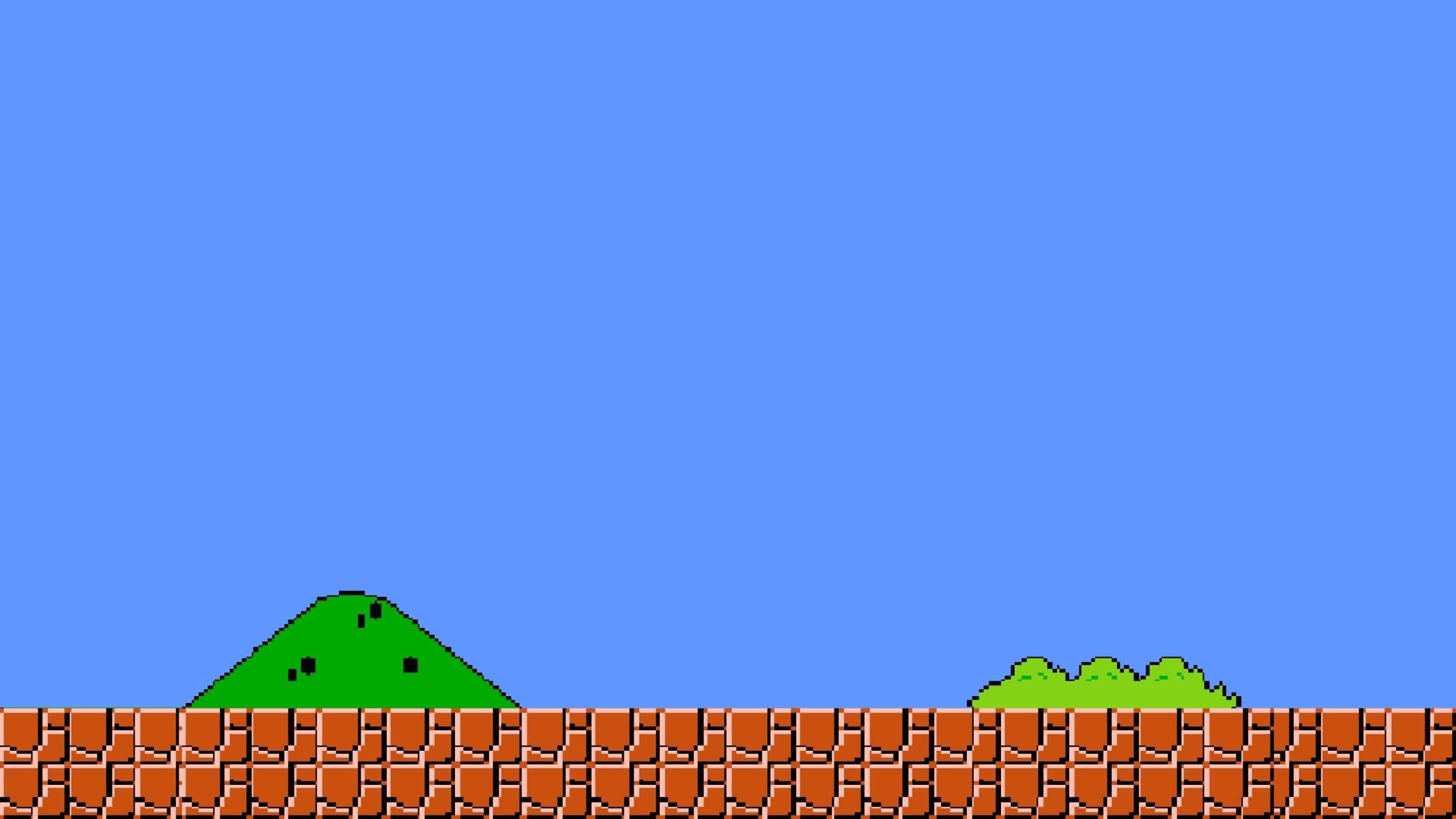 Retro Gaming 桌布 壁紙 — 像素化的綠色山丘坐落在棕色磚砌平台上，上方是純藍色的天空，呈現經典的8位元電玩風格。