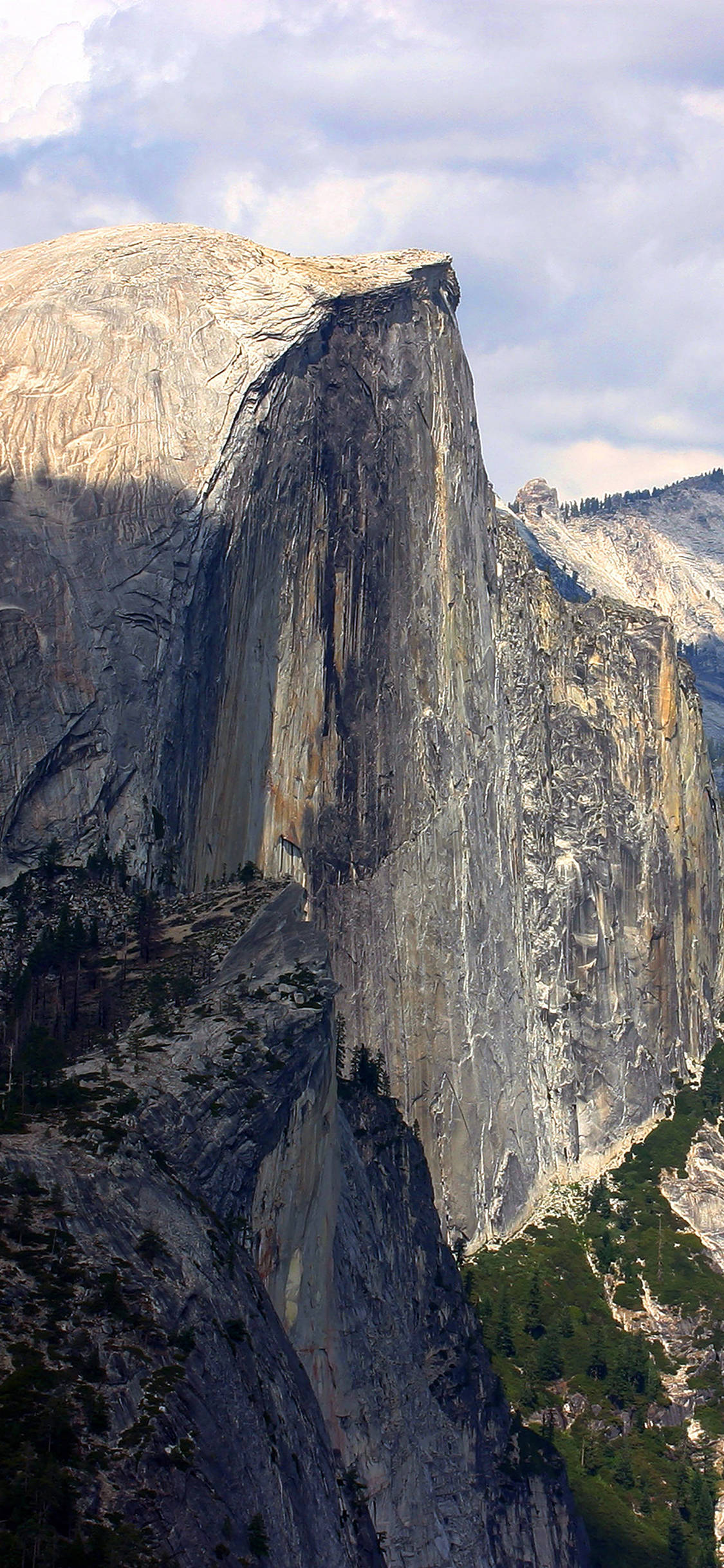 Yosemite iPhone 桌布 壁紙 — 優勝美地國家公園中半圓頂的花崗岩懸崖高聳，沐浴在柔和日光中，上方有零星雲朵。