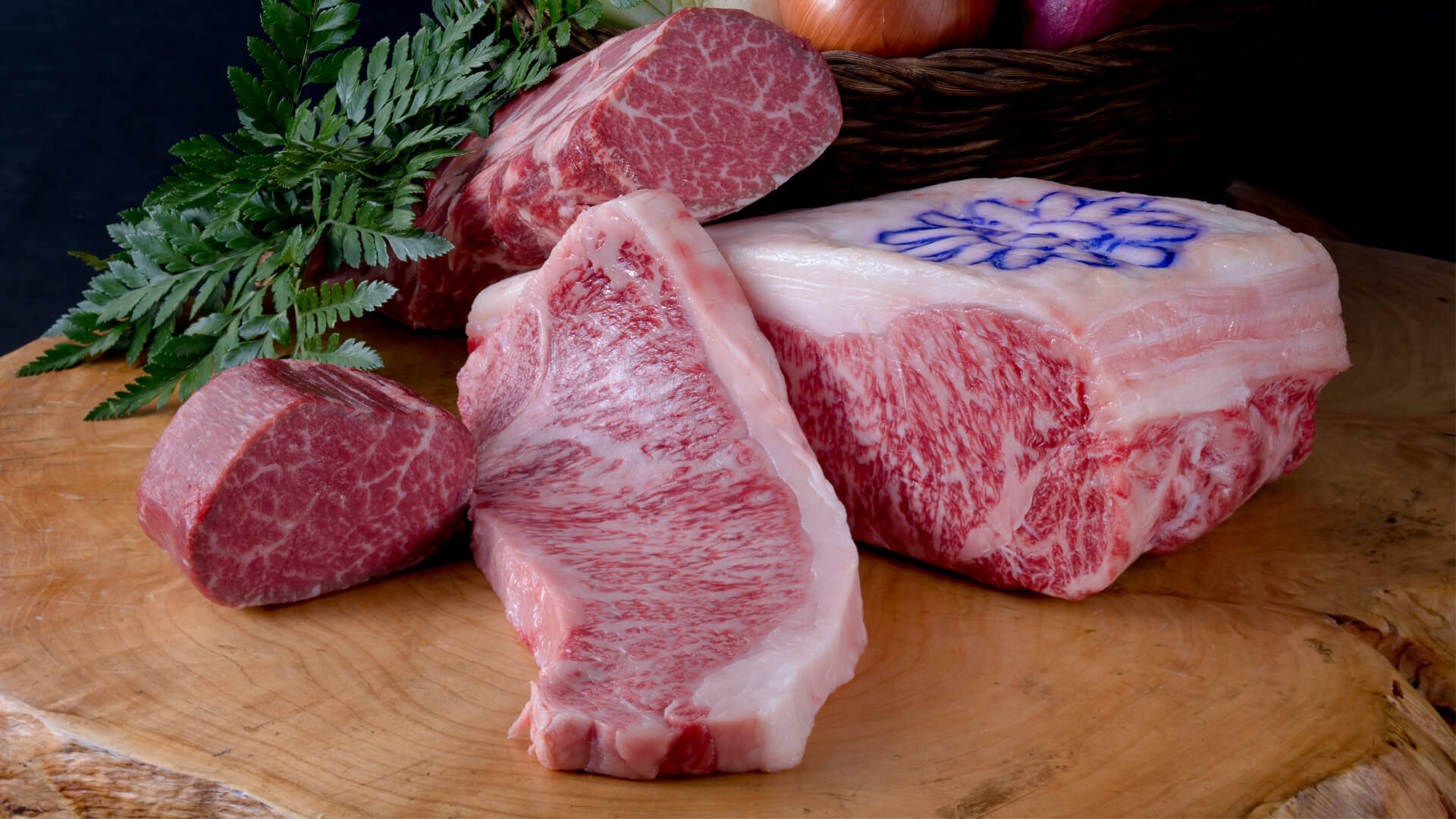 meat 桌布 壁紙 — 優質大理石紋牛肉切塊帶有複雜的脂肪紋理，放在質樸的木板上，旁邊是新鮮的蕨類植物和洋蔥。