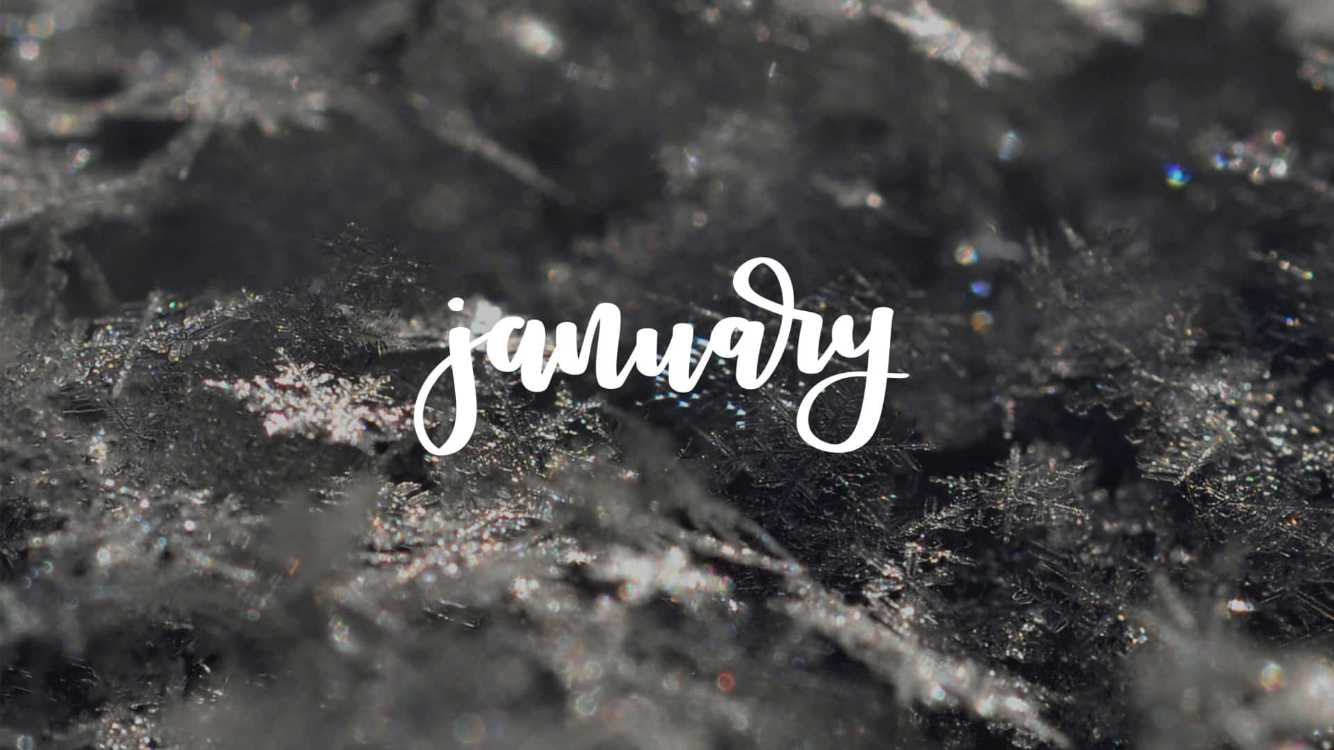 一月 桌布 壁紙 — 優雅白色字體的「january」一詞覆蓋在深色表面上精緻霜凍圖案的特寫，閃爍著冰晶光澤。