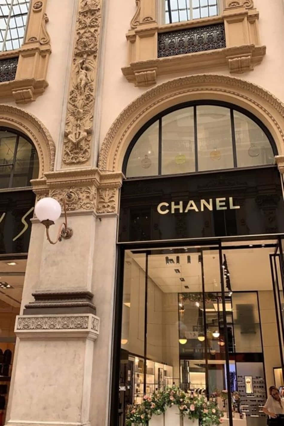 Luxury Brands 桌布 壁紙 — 優雅的 Chanel 精品店，飾有華麗的石拱門和展示奢侈品的玻璃窗。