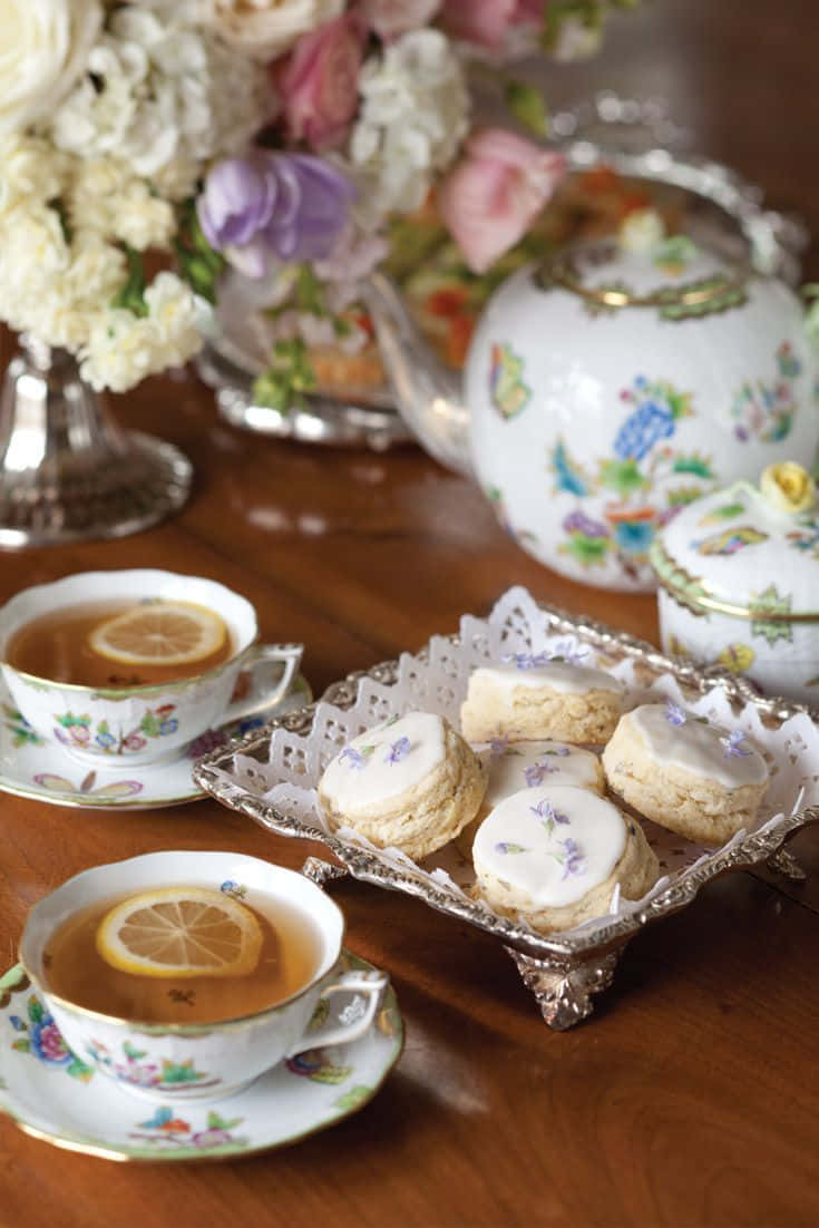 Teatime 桌布 壁紙 — 優雅的下午茶擺設，配有花卉茶杯、檸檬片和薰衣草餅乾，置於木桌上。