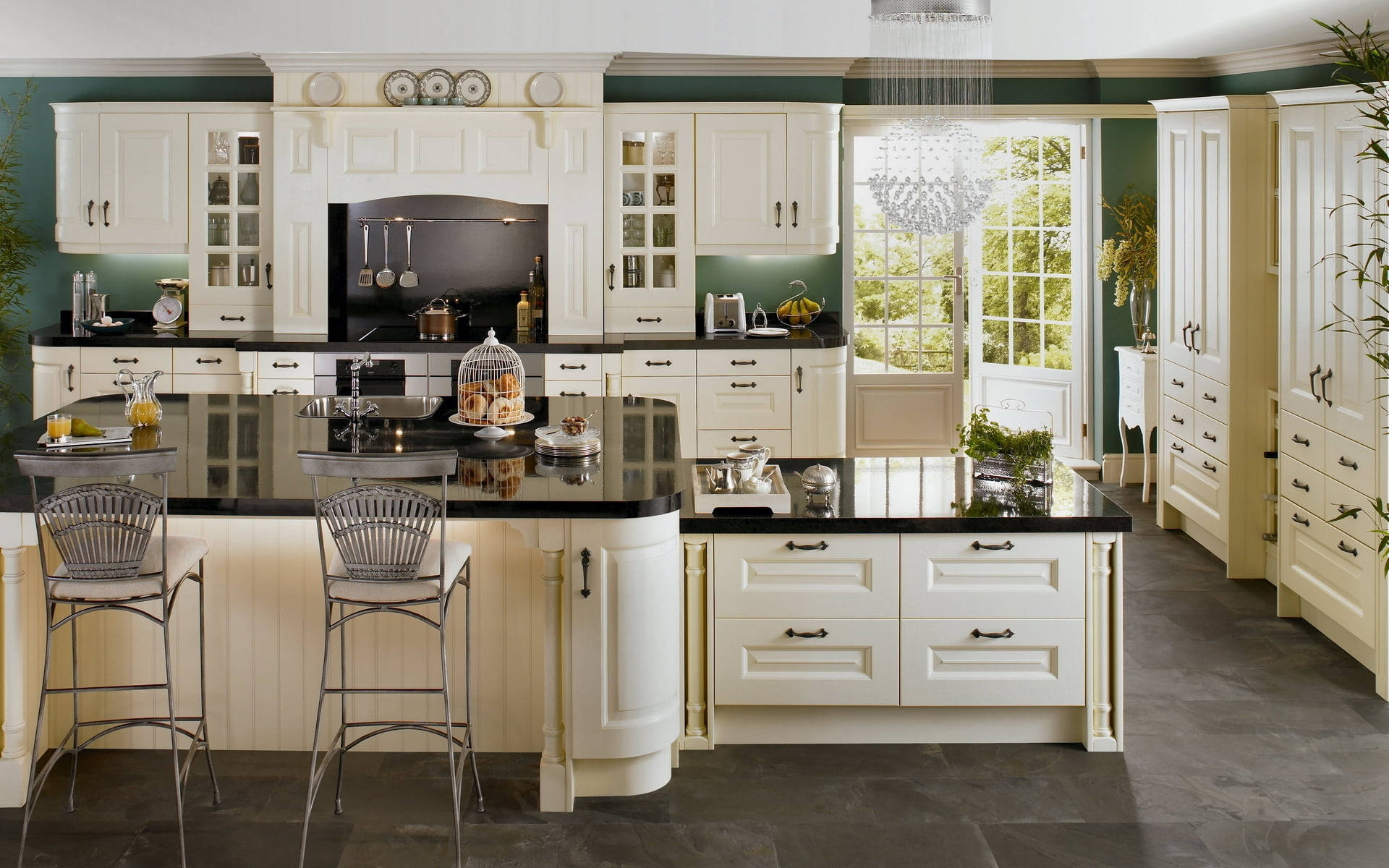 Kitchen Design 桌布 壁紙 — 優雅的奶油色廚房，配有黑色檯面和水晶吊燈，可透過玻璃門欣賞綠意。