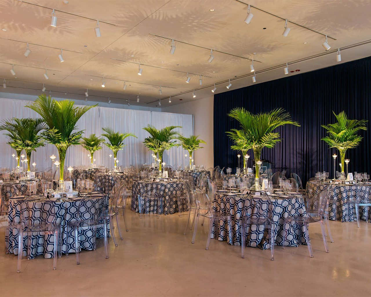 Corporate Event 桌布 壁紙 — 優雅的宴會廳，圓桌鋪有圖案亞麻布，高大的棕櫚樹中心裝飾，上方有明亮的吊燈。