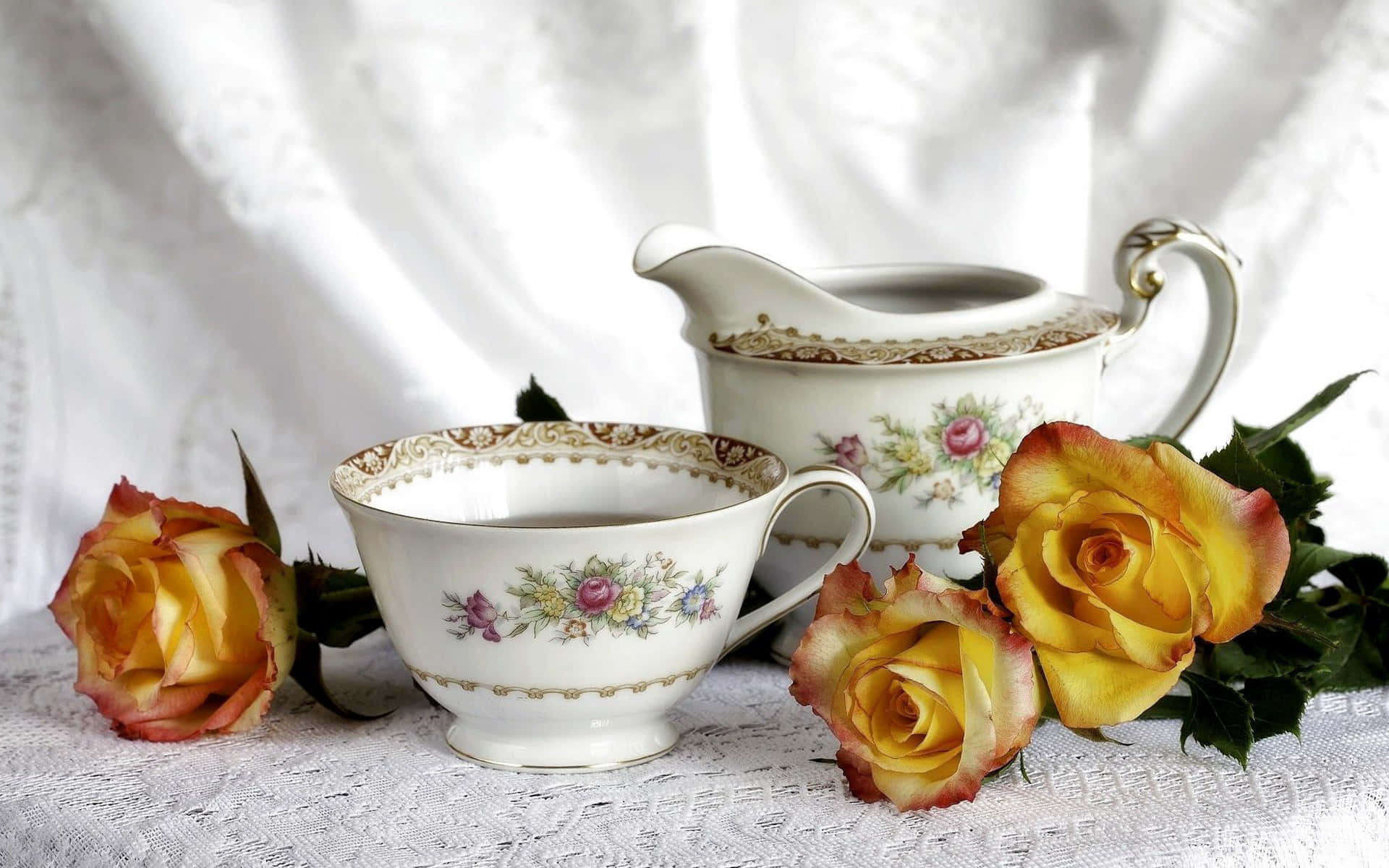 Floral Tea 桌布 壁紙 — 優雅的復古瓷器茶具套裝，飾有花卉圖案，擺在蕾絲桌布上，旁邊是鮮豔的黃玫瑰。