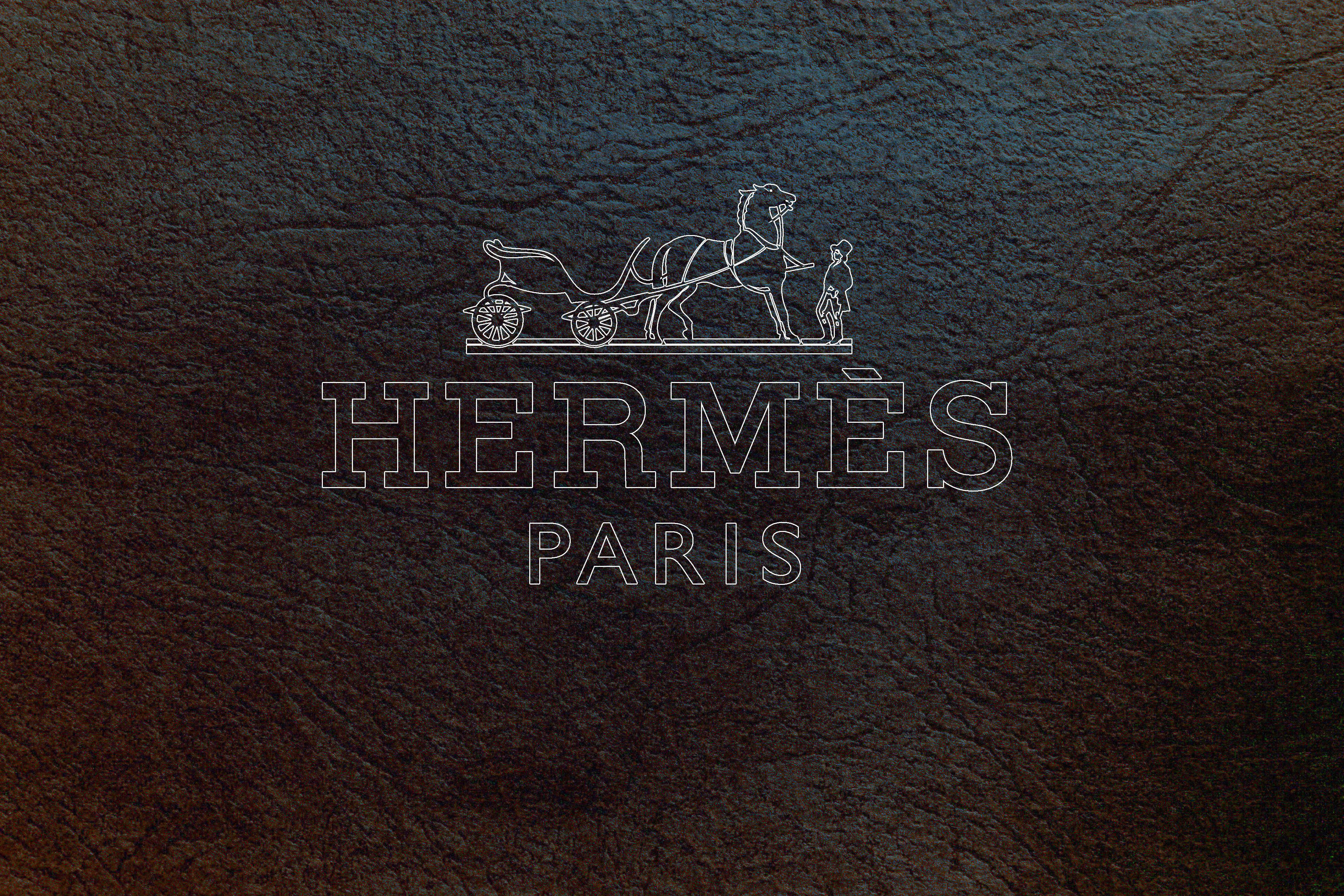 Hermes 桌布 壁紙 — 優雅的愛馬仕巴黎標誌以白色壓印在濃郁的深棕色紋理皮革上。
