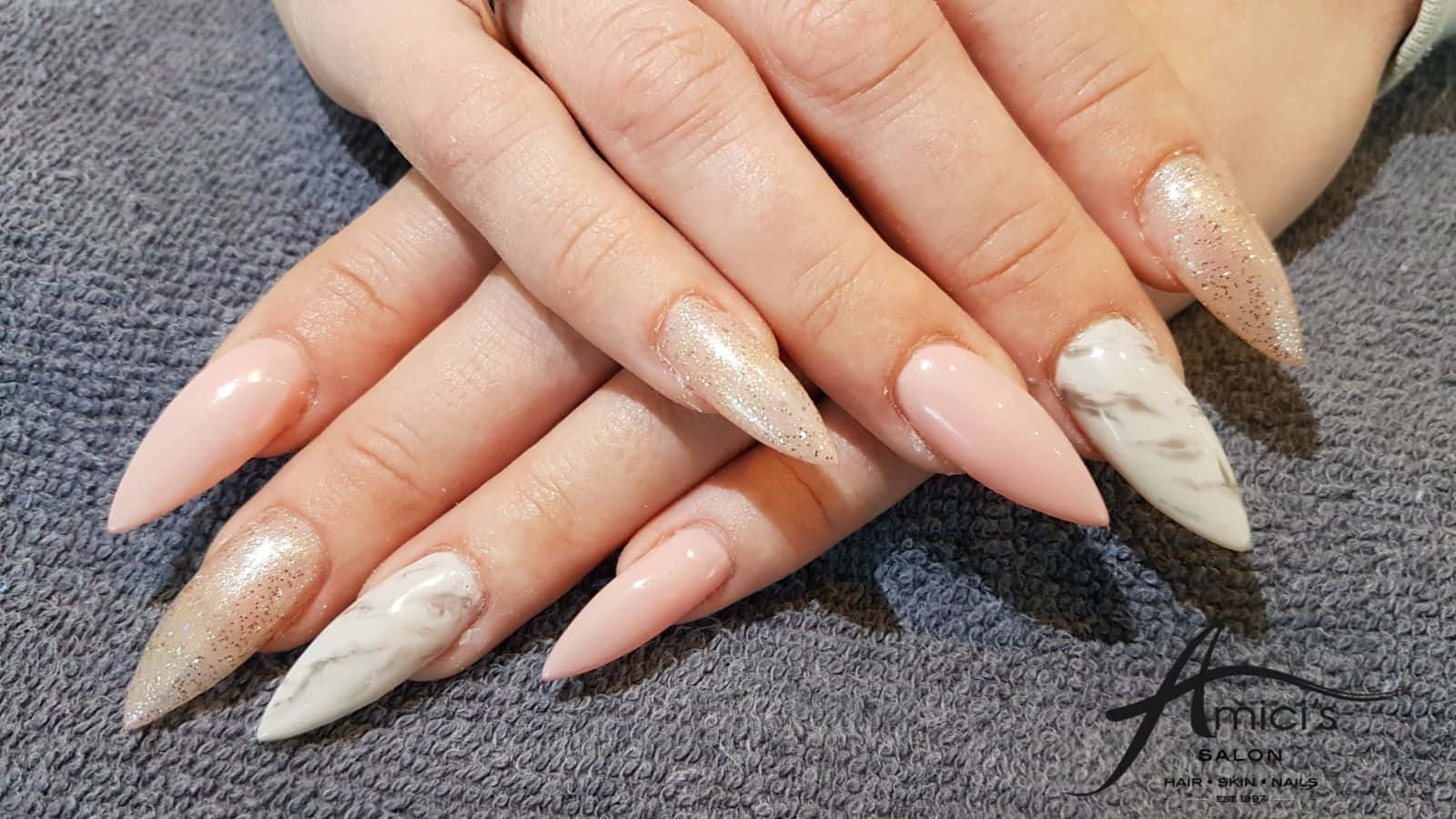 Pink Nails 桌布 壁紙 — 優雅的手，帶有長尖形指甲，採用裸色閃粉和白色大理石設計，放在灰色毛巾上。