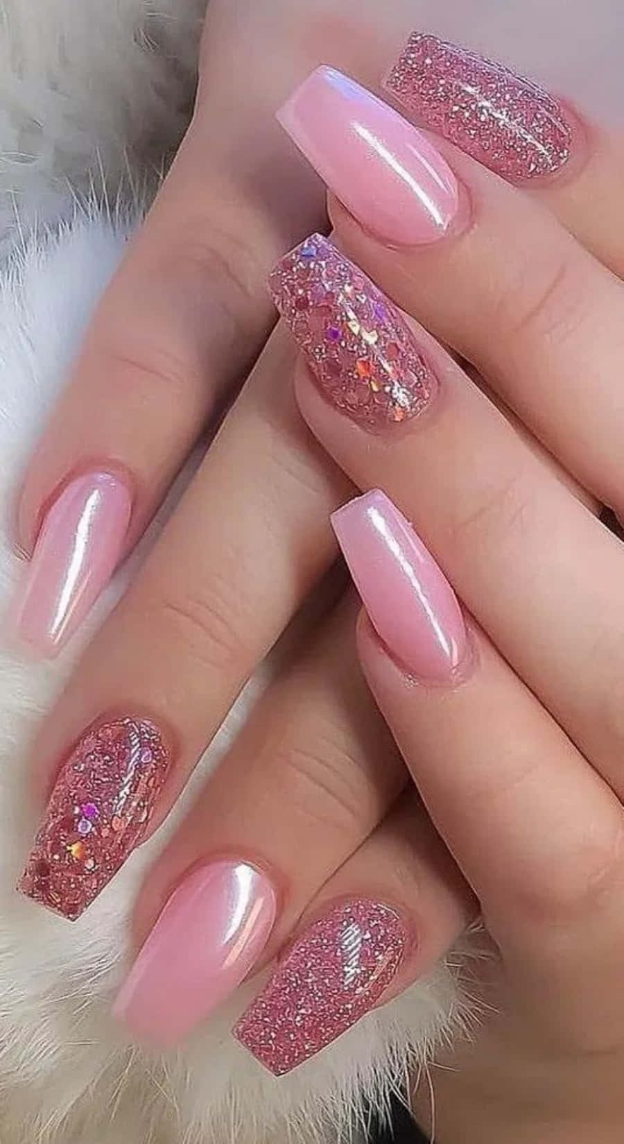 Pink Nail Art 桌布 壁紙 — 優雅的手部，帶有光澤的粉紅色指甲，飾有閃爍的全息裝飾，放在柔軟的白色毛絨表面上。