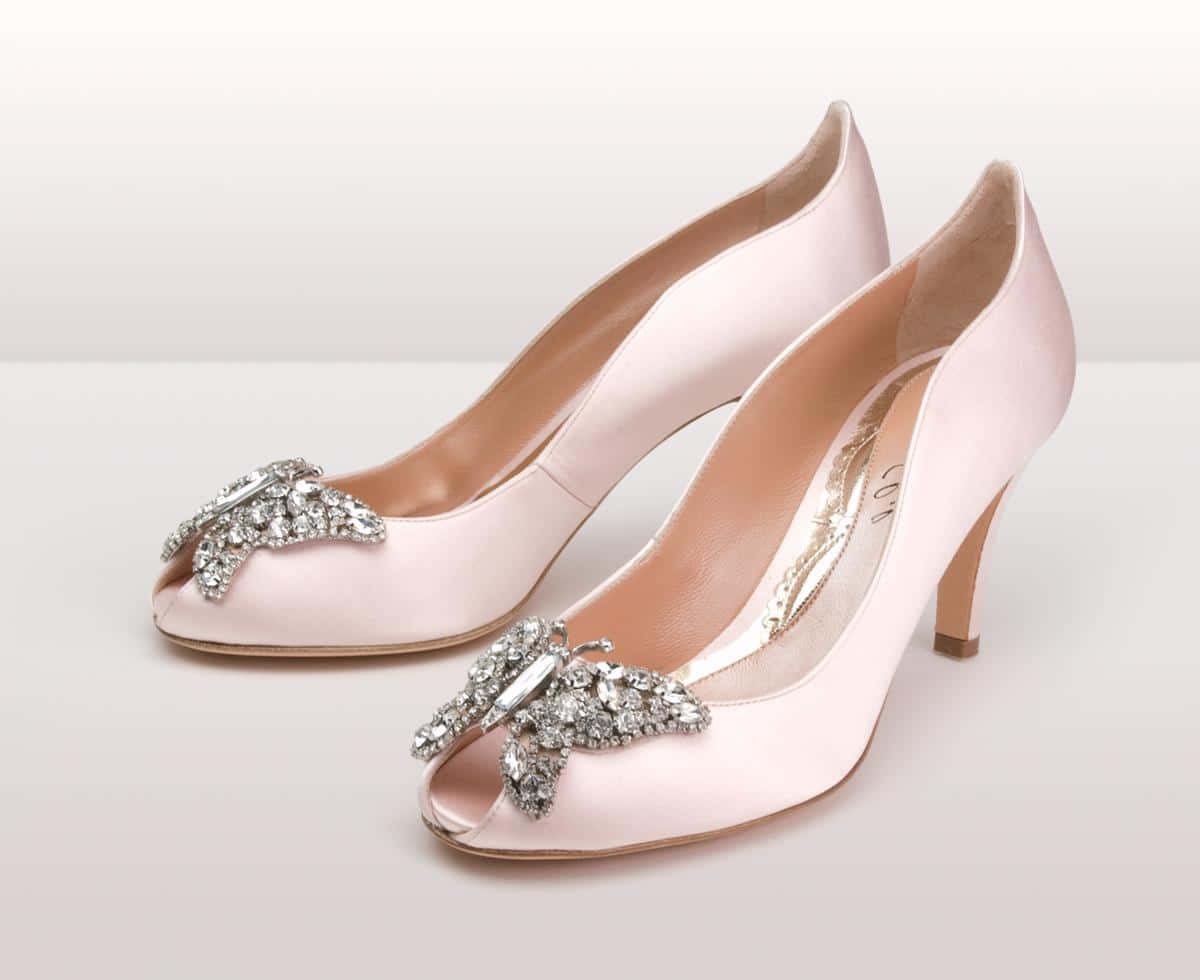 Pink Shoes 桌布 壁紙 — 優雅的淺粉紅色緞面魚嘴高跟鞋，飾有閃亮的水晶蝴蝶裝飾，背景為純白色。
