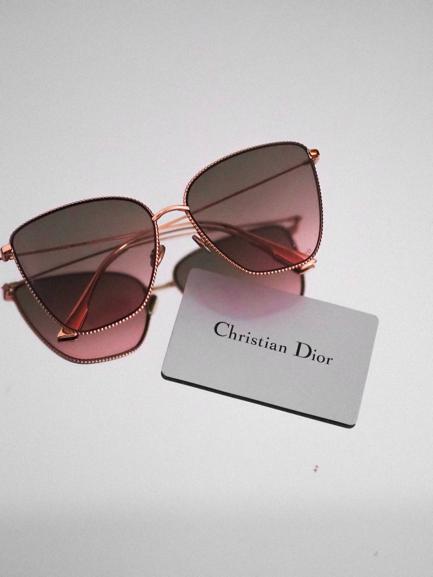 Christian Dior太陽眼鏡，玫瑰金色鏡框，粉紅色鏡片，白色背景。 — Dior 動態 壁紙