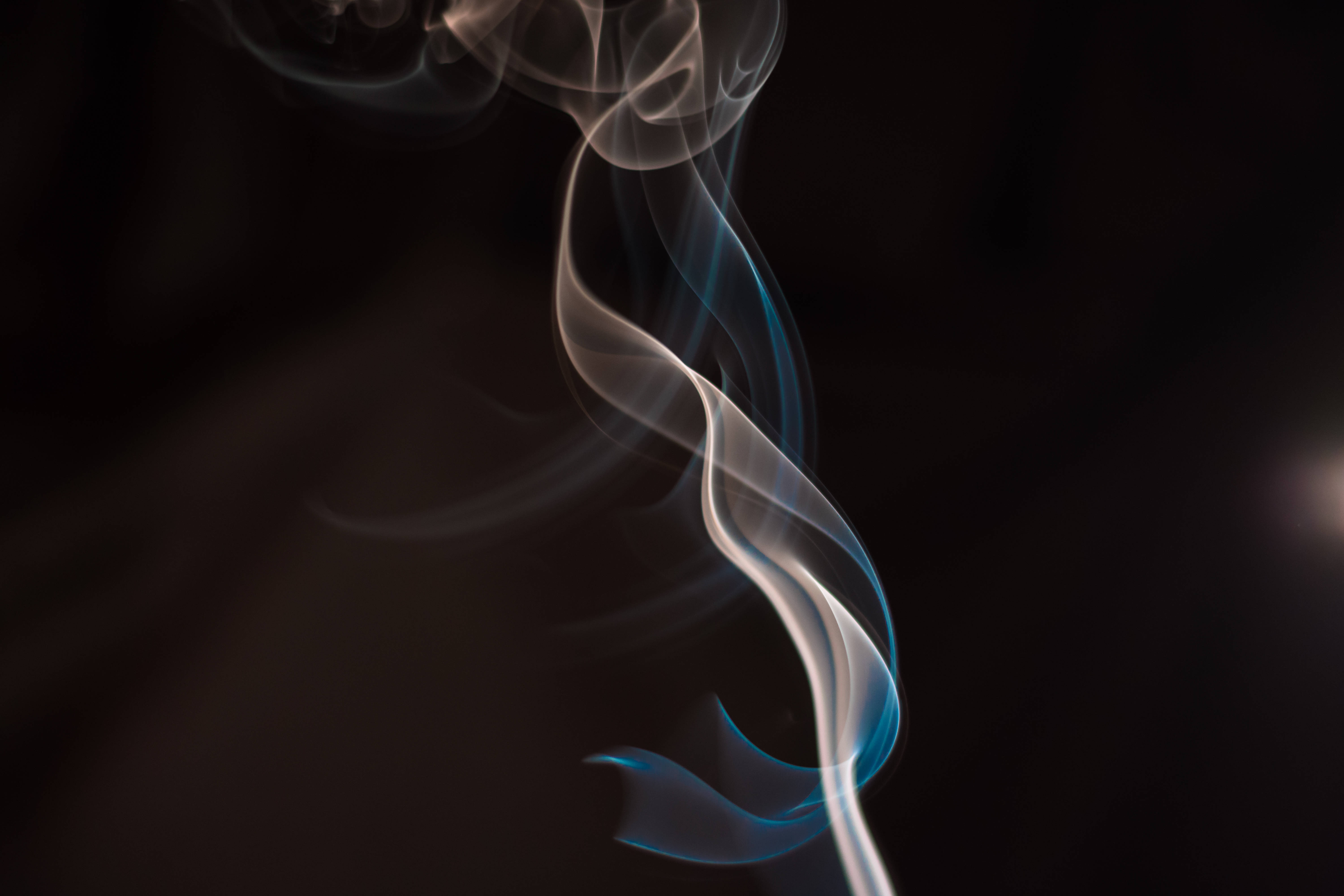 抽菸 桌布 壁紙 — 優雅的白色和藍色漩渦煙霧在深黑色背景上優雅升起。