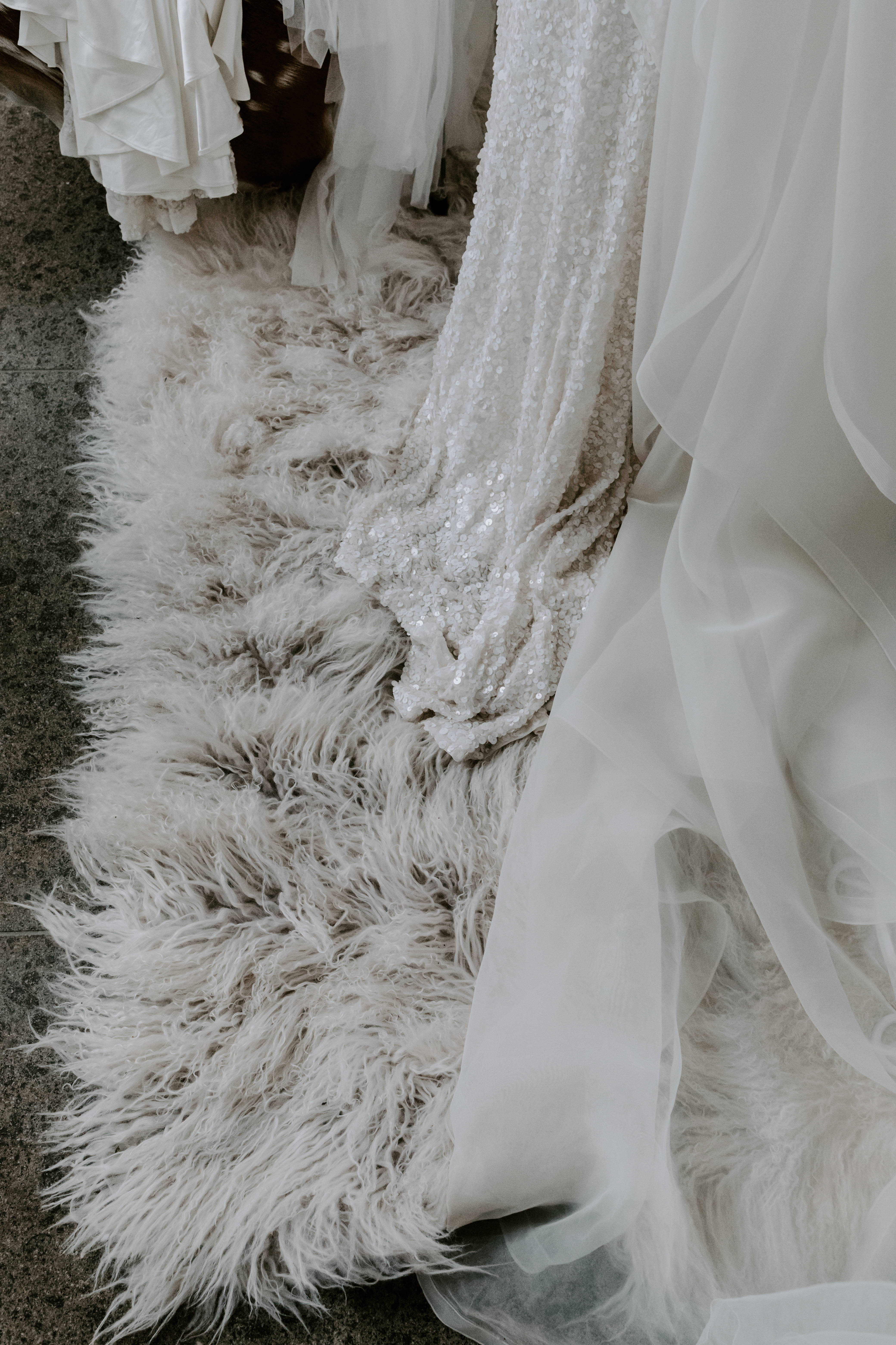 Wedding Aesthetic 桌布 壁紙 — 優雅的白色婚紗帶有亮片細節，優雅地放置在蓬鬆的白色毛皮地毯上。