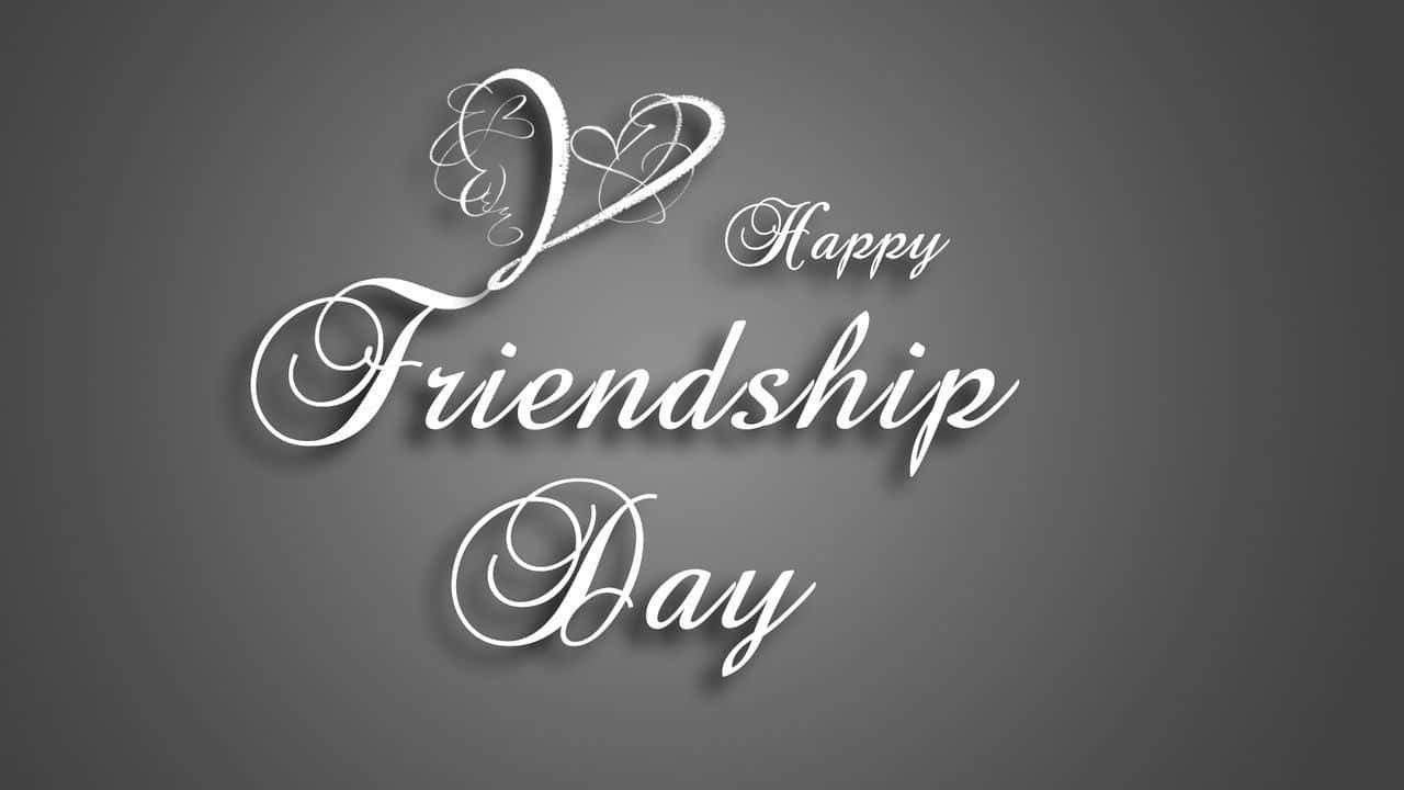 友誼日 桌布 壁紙 — 優雅的白色草書文字寫著「Happy Friendship Day」，並帶有心形圖案，背景為柔和的灰色漸變。