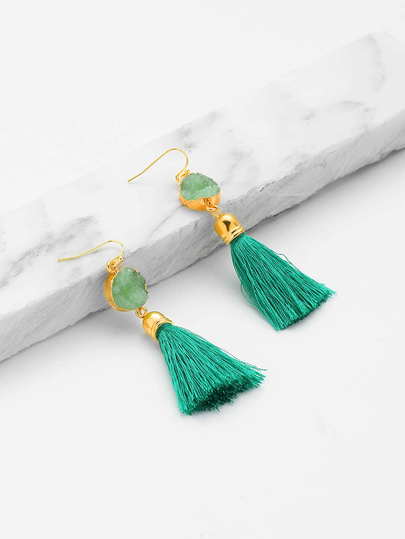 Earrings 桌布 壁紙 — 優雅的綠色流蘇耳環搭配金色點綴，放置在白色大理石板上，背景為純白色。